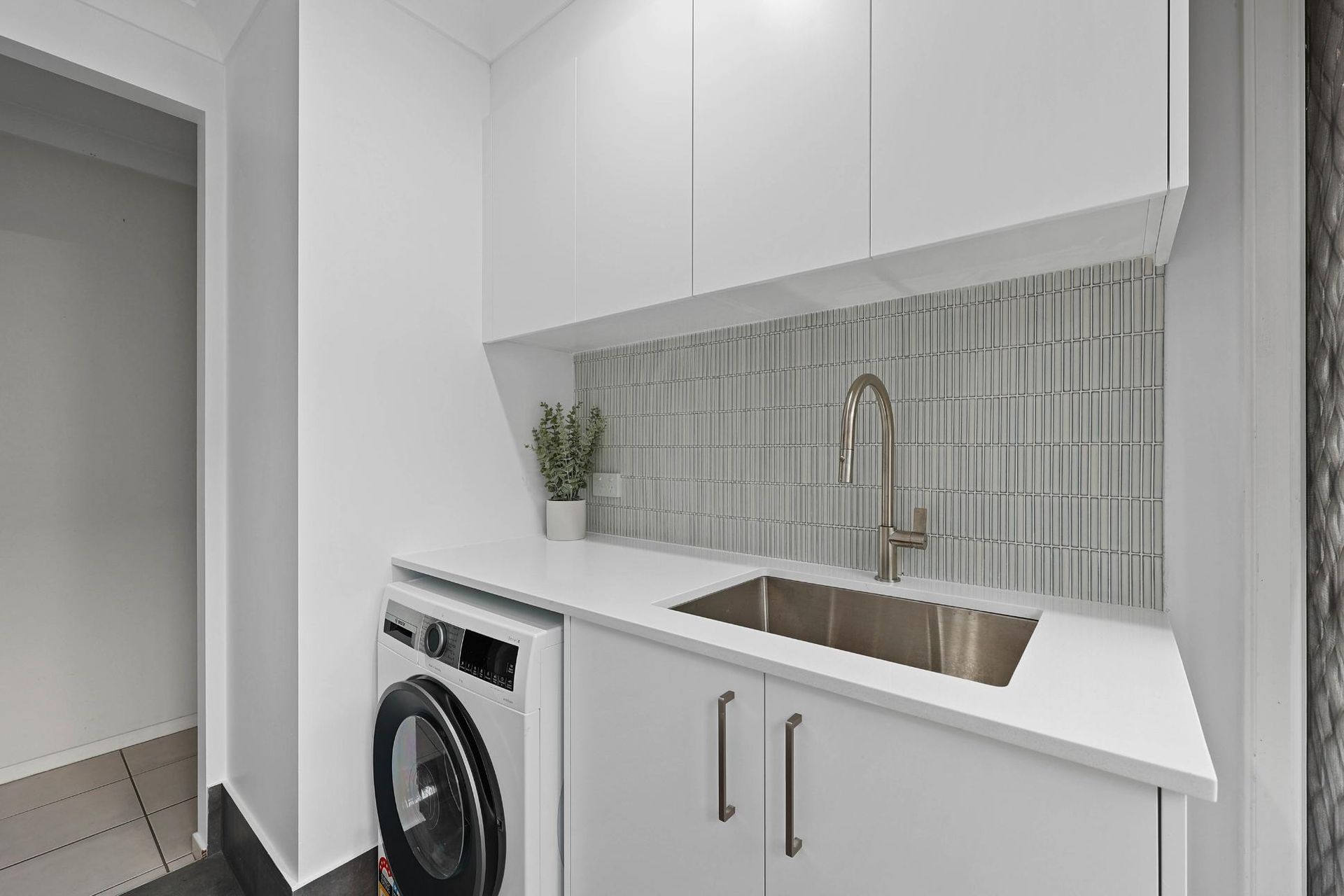 Modern White Laundry Room With Stacked Washer — Above & Beyond Interiors in Smeaton Grange, NSW