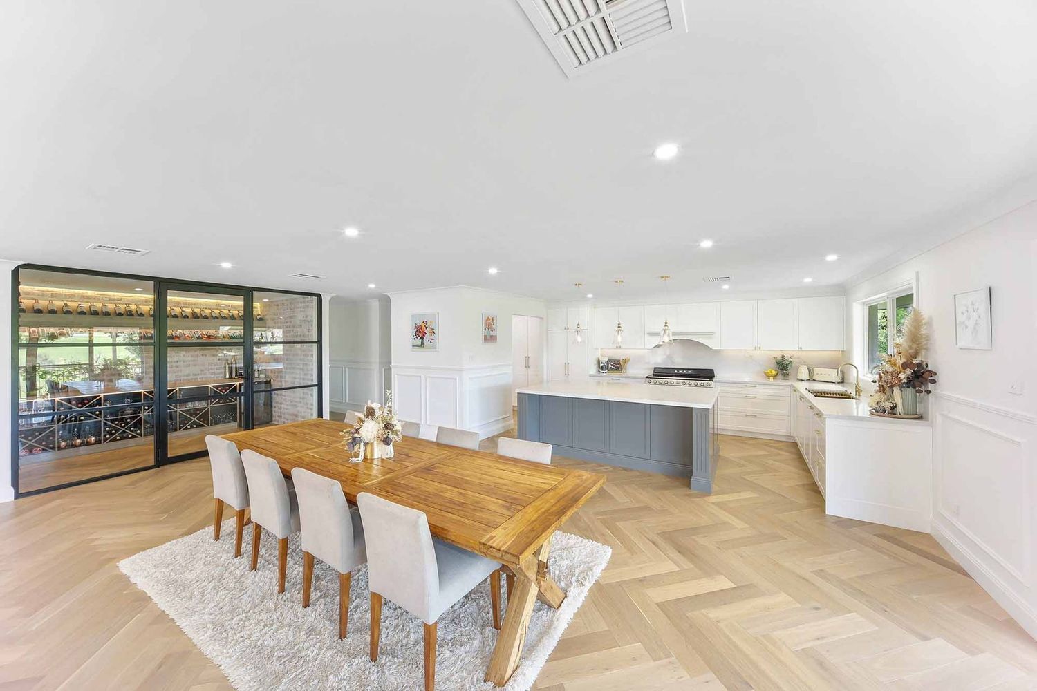 Bright Open-plan Dining and Kitchen With Wooden Table — Above & Beyond Interiors in Smeaton Grange, NSW