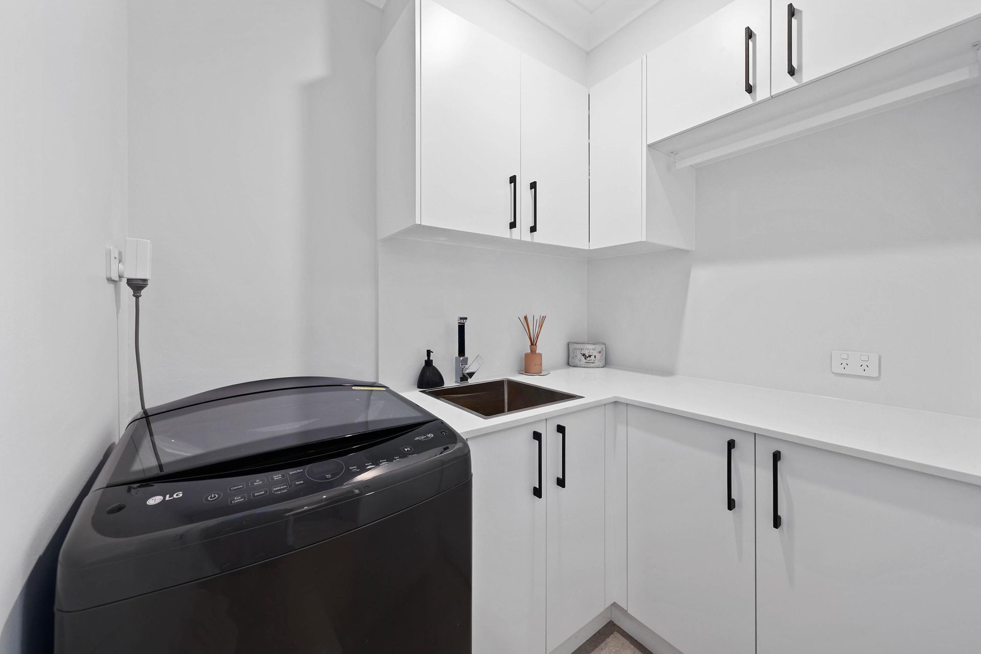 Laundry Room With a Black Washing Machine — Above & Beyond Interiors in Smeaton Grange, NSW