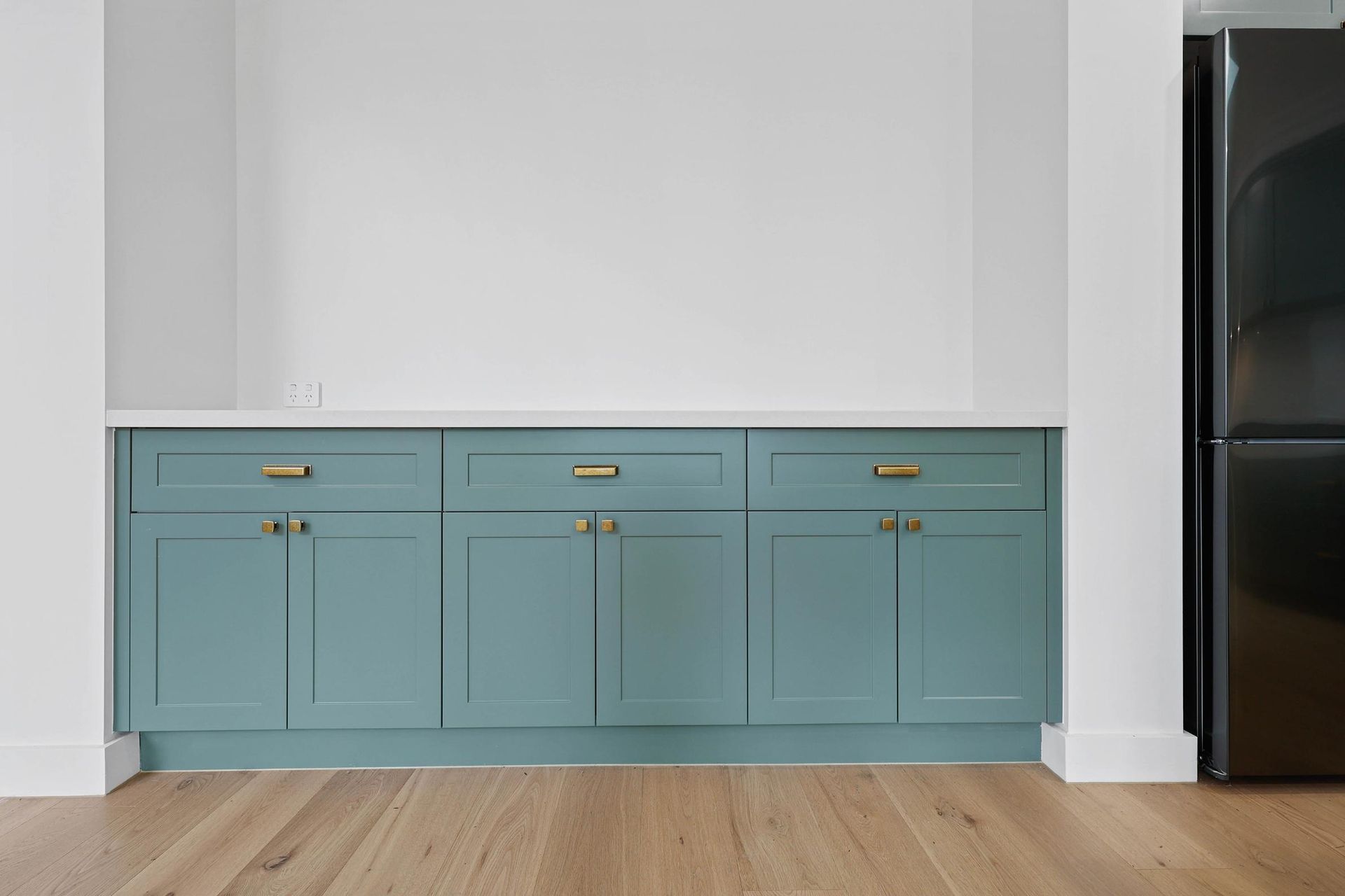 Built-in Teal Cabinets Under a Blank White Wall in a Modern Room — Above & Beyond Interiors in Smeaton Grange, NSW