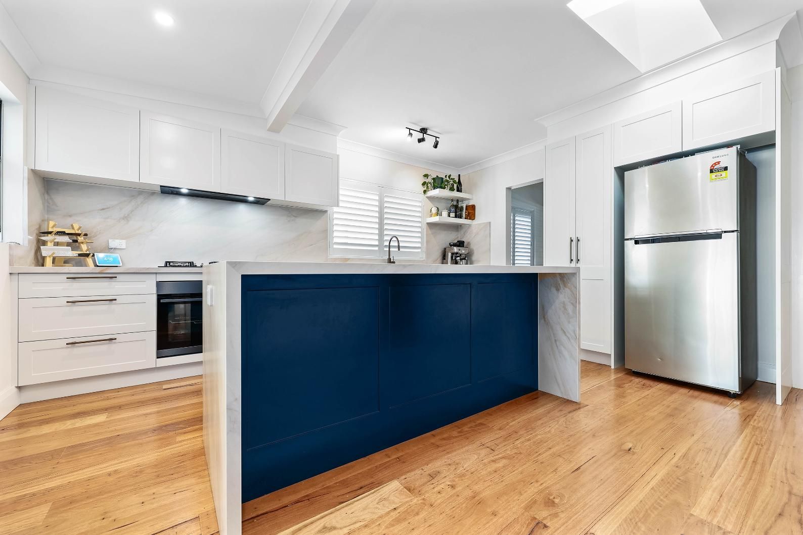 Bright Modern Kitchen With Blue Island, White Cabinets — Above & Beyond Interiors in Smeaton Grange, NSW