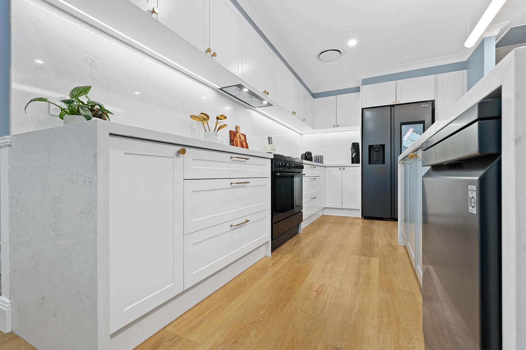 Modern White Kitchen With Wood Floor — Above & Beyond Interiors in Smeaton Grange, NSW
