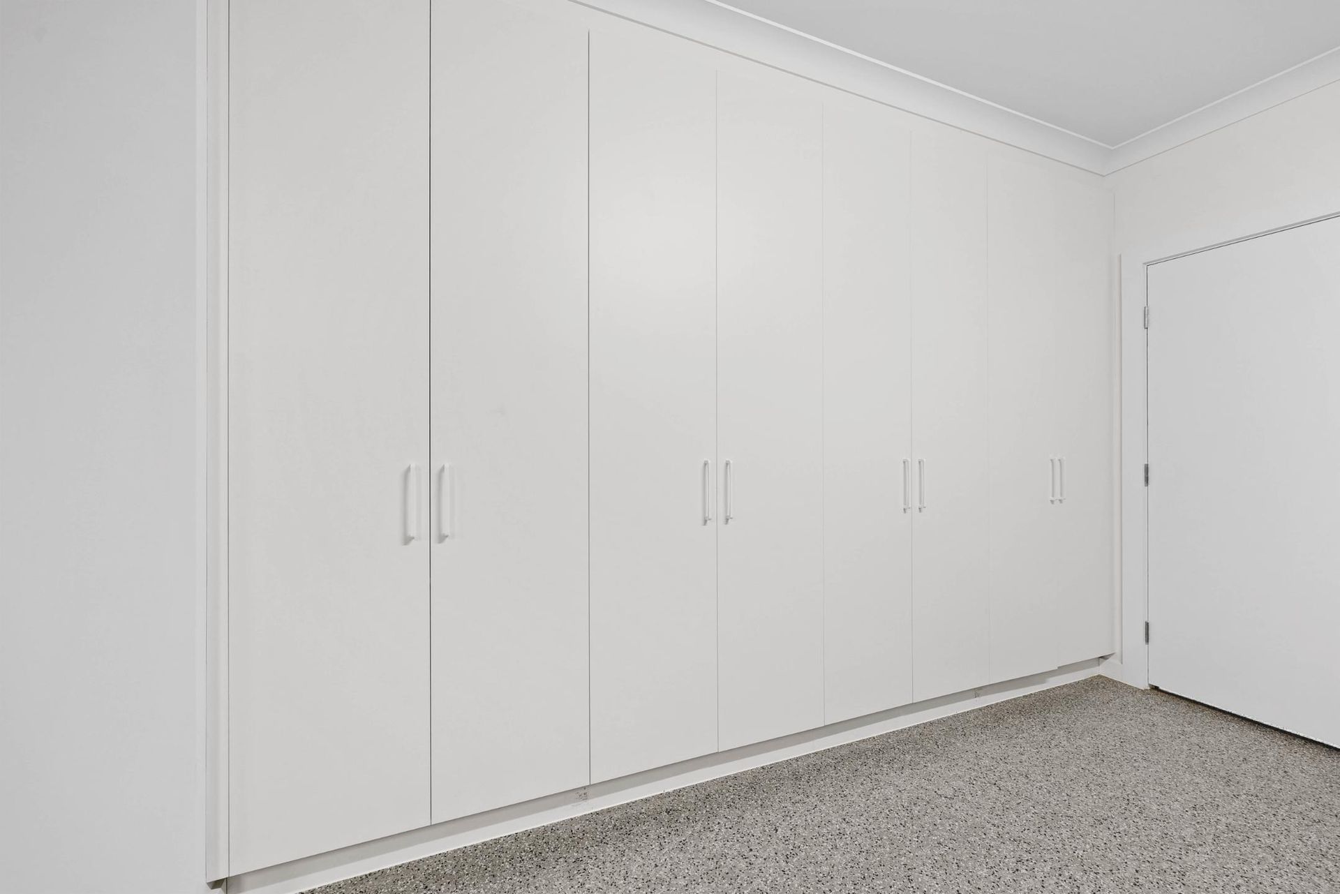 White Built-in Closet Cabinets Along a Speckled Carpeted Wall — Above & Beyond Interiors in Smeaton Grange, NSW