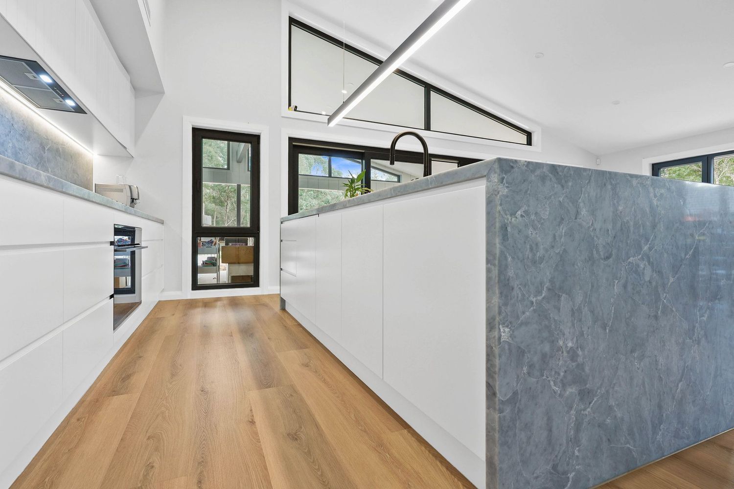 Modern White Kitchen With Wood Floor, Black-framed Windows — Above & Beyond Interiors in Smeaton Grange, NSW