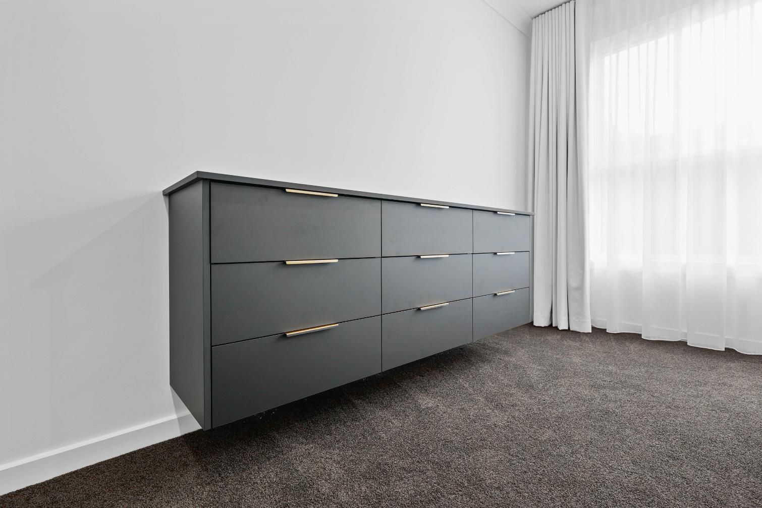 Gray Dresser Against a White Wall in a Carpeted Room With Sheer Curtains — Above & Beyond Interiors in Smeaton Grange, NSW