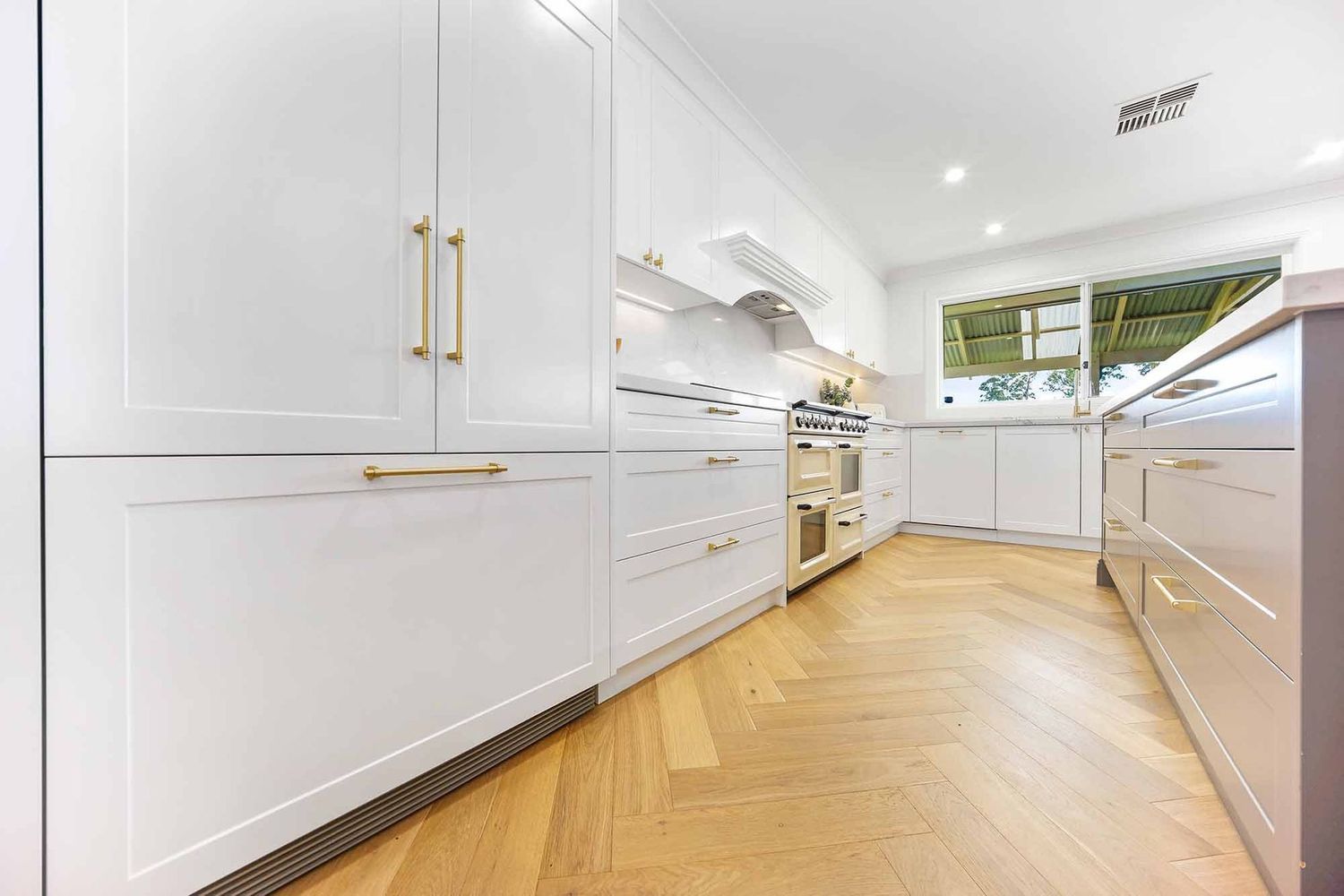 Bright White Galley Kitchen With Wood Floors — Above & Beyond Interiors in Smeaton Grange, NSW