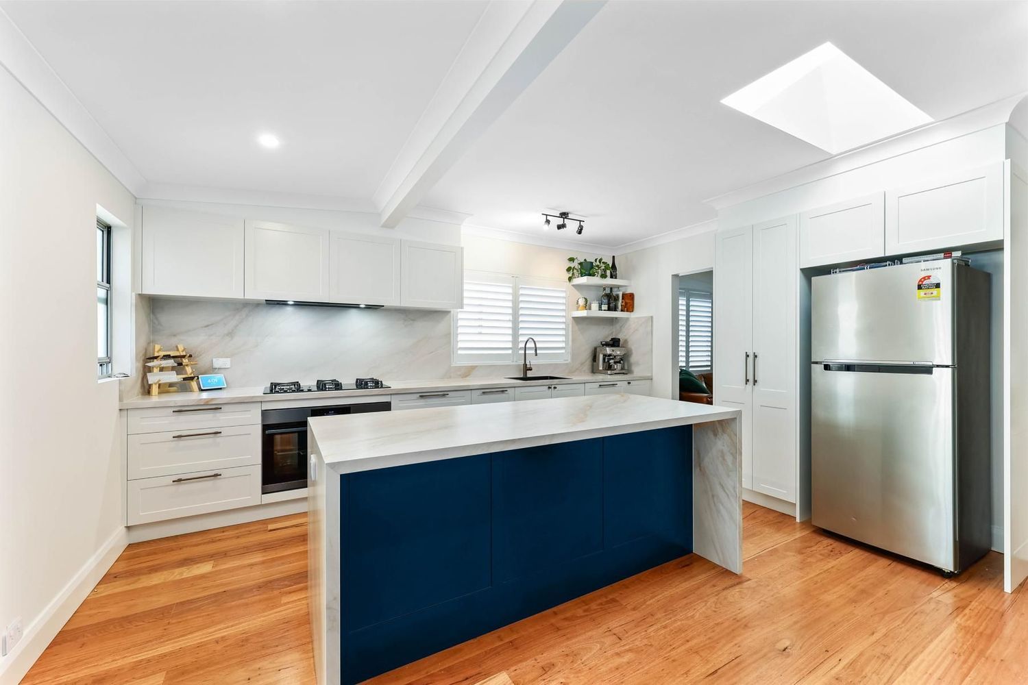 Bright Modern Kitchen With Blue Island, White Cabinets — Above & Beyond Interiors in Smeaton Grange, NSW