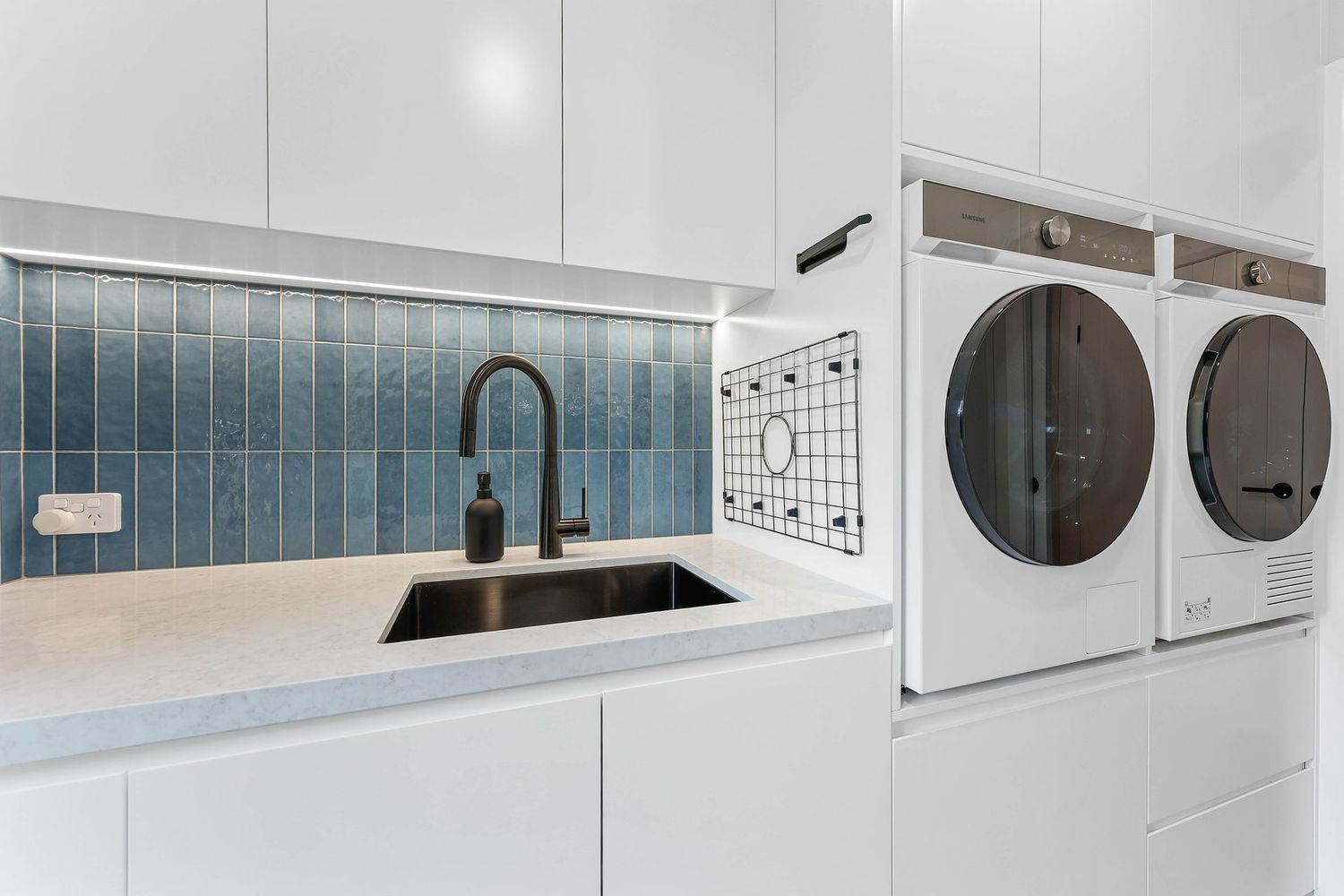 Modern White Laundry Room With Stacked Washer — Above & Beyond Interiors in Smeaton Grange, NSW
