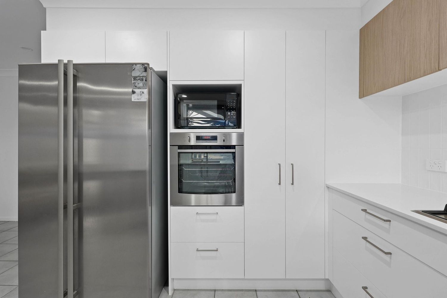 Modern White Kitchen With Stainless Steel Fridge — Above & Beyond Interiors in Smeaton Grange, NSW