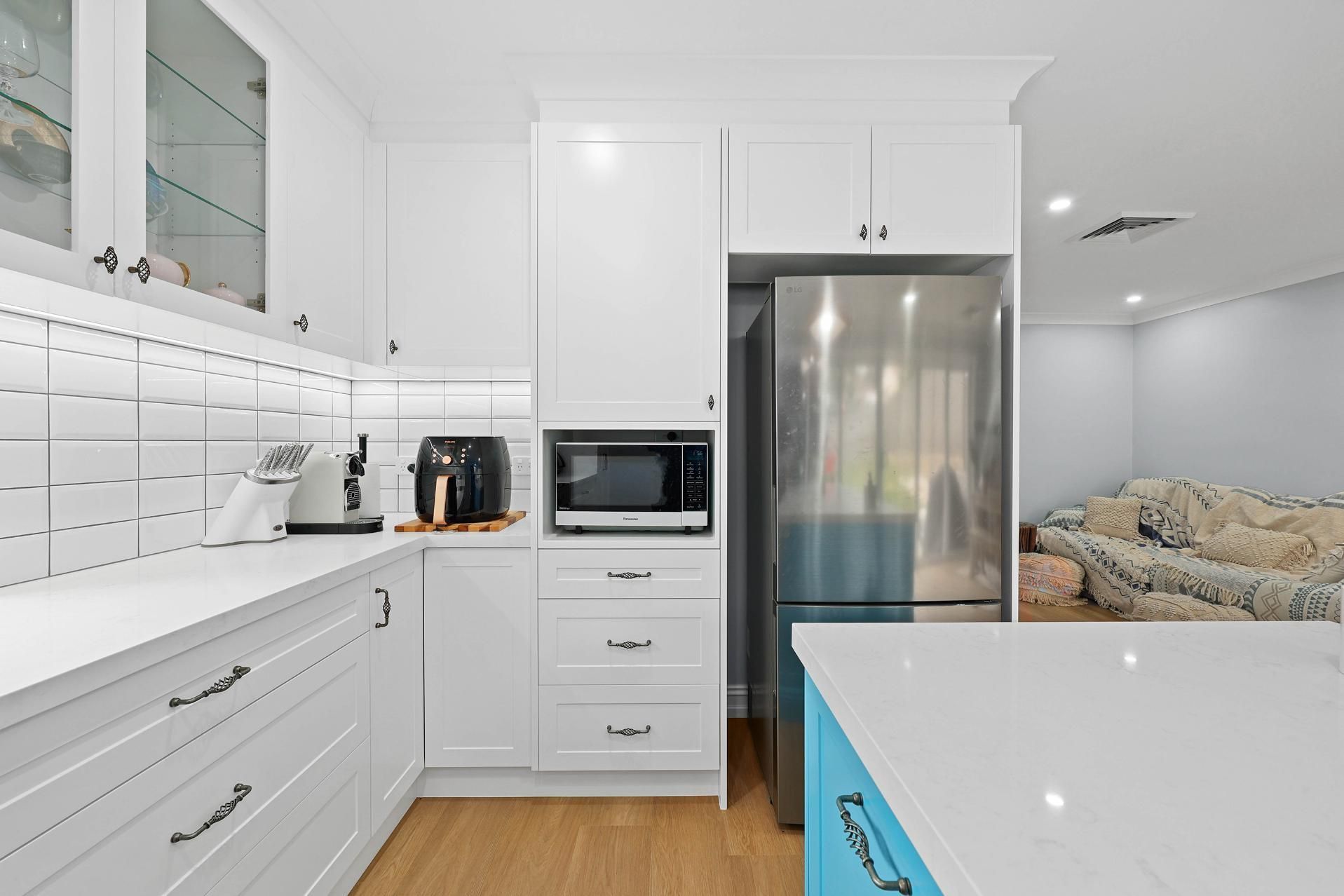 Bright White Kitchen With Stainless Steel Fridge — Above & Beyond Interiors in Smeaton Grange, NSW