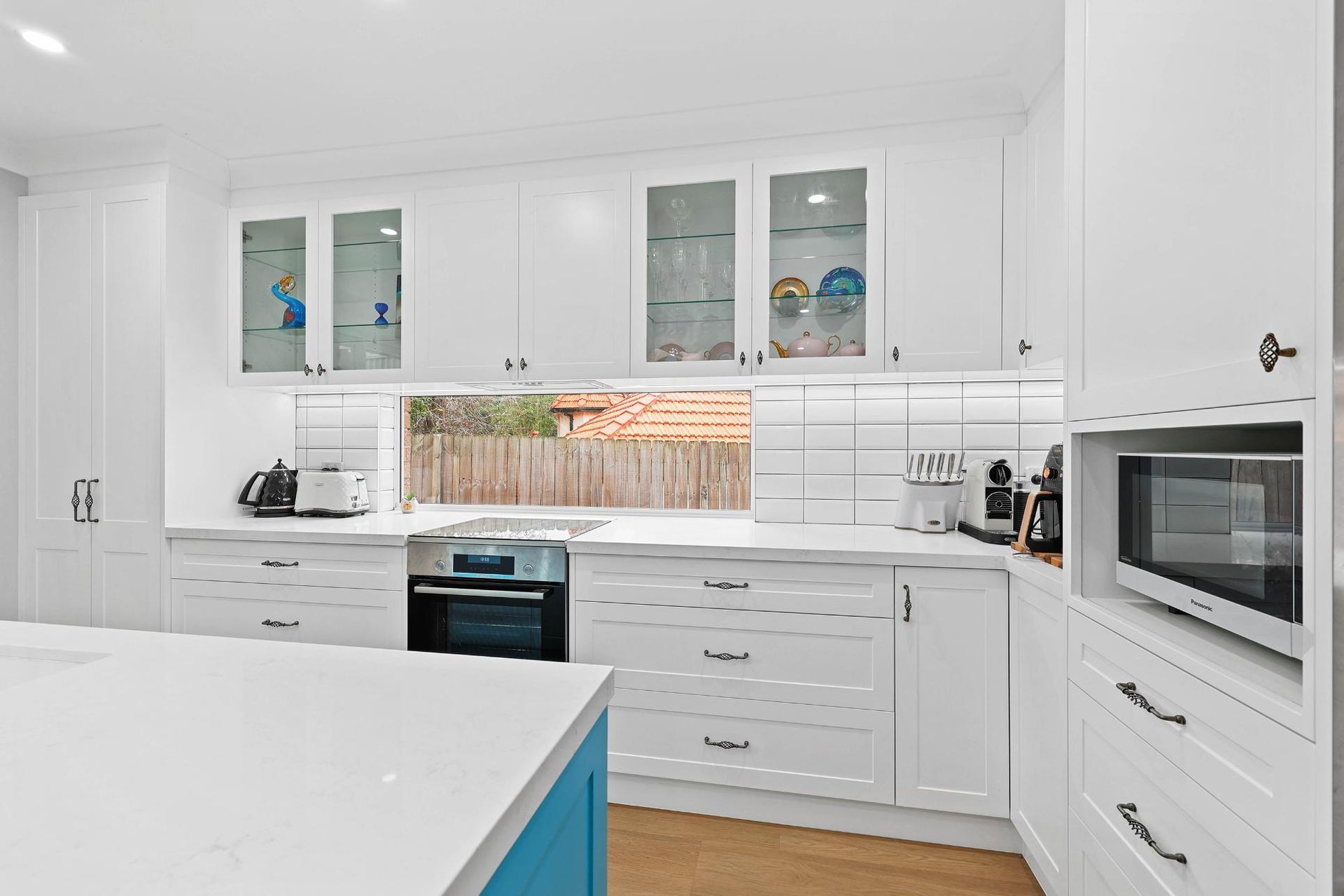 Bright White Kitchen With Blue Island, Stainless Stove — Above & Beyond Interiors in Smeaton Grange, NSW