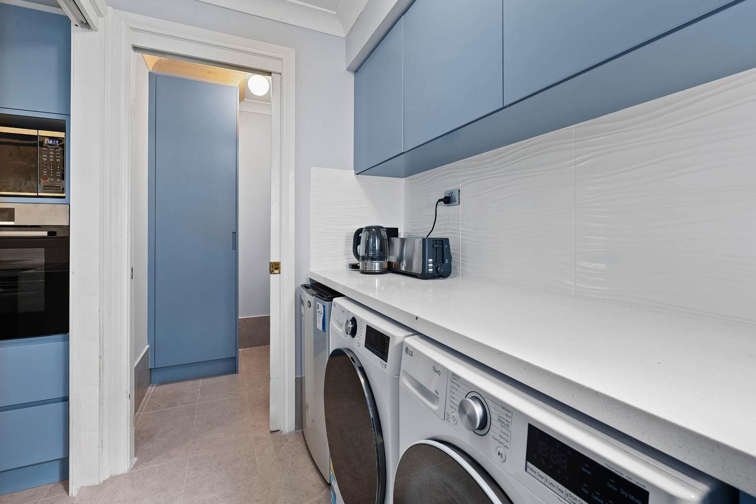 Narrow Laundry Room With Blue Cabinets — Above & Beyond Interiors in Smeaton Grange, NSW
