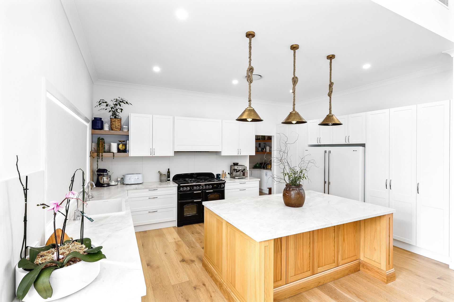 Bright White Modern Kitchen With Wood Island — Above & Beyond Interiors in Smeaton Grange, NSW