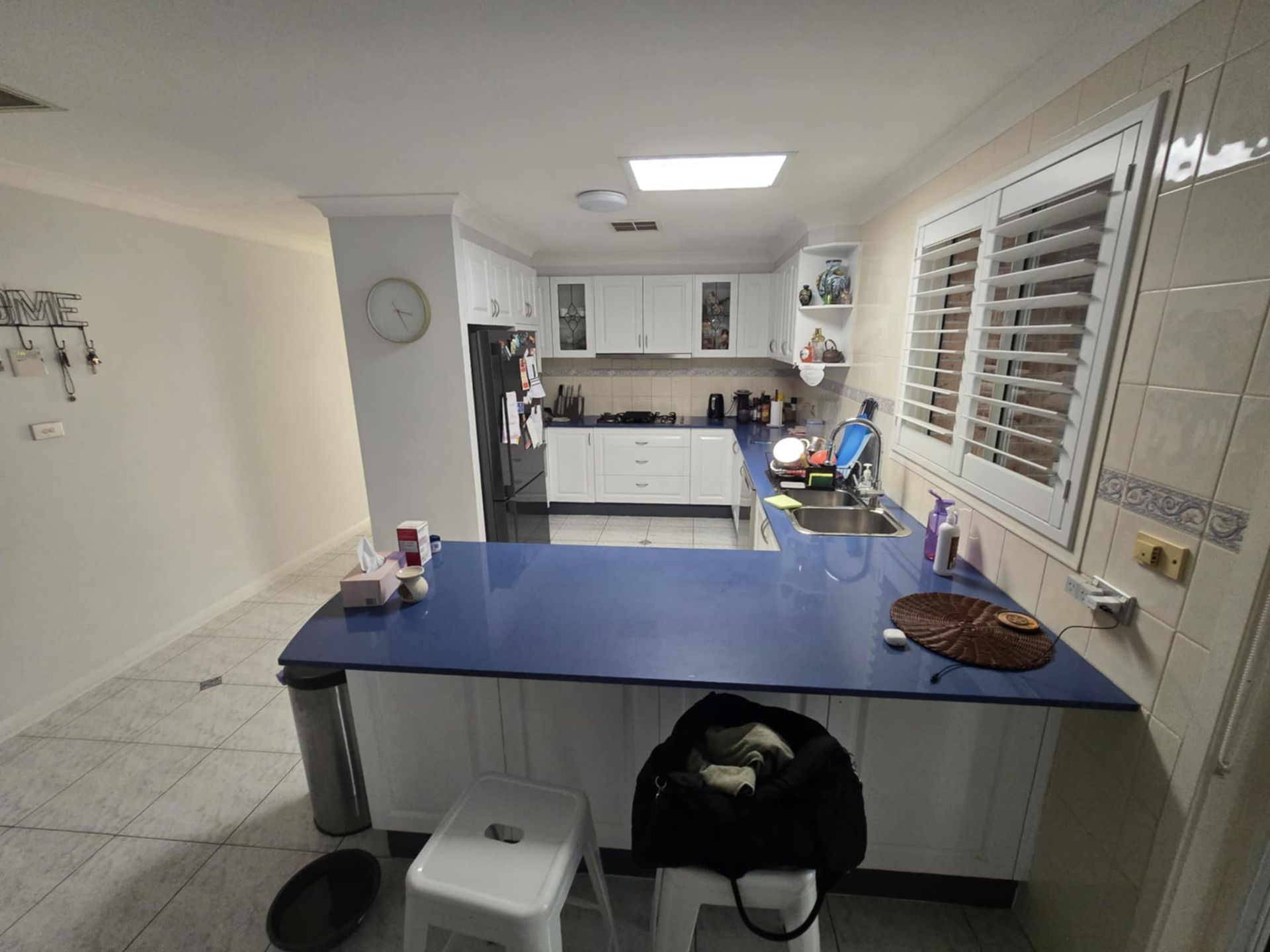 Bright Kitchen with Blue Island, Cabinets, Tiled Floor, and Window Shutters — Above & Beyond Interiors in Smeaton Grange, NSW