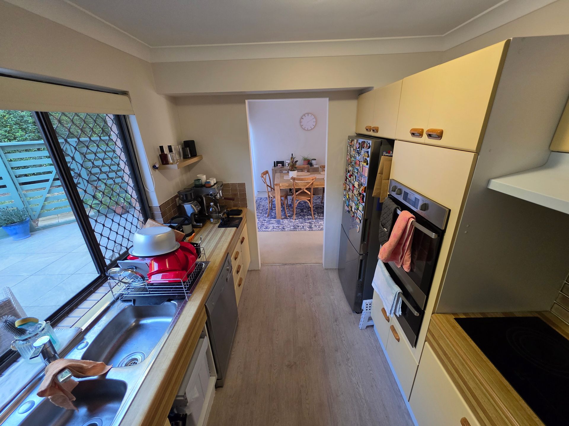 A Modern Kitchen with Light Wood Cabinets, Window Sink, and Dining Area Visible — Above & Beyond Interiors in Smeaton Grange, NSW