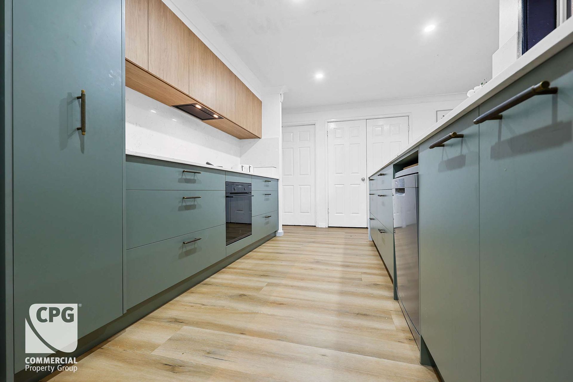 Modern Kitchen with Light Wood Floor, White Walls, and Stainless Steel Appliances — Above & Beyond Interiors in Smeaton Grange, NSW