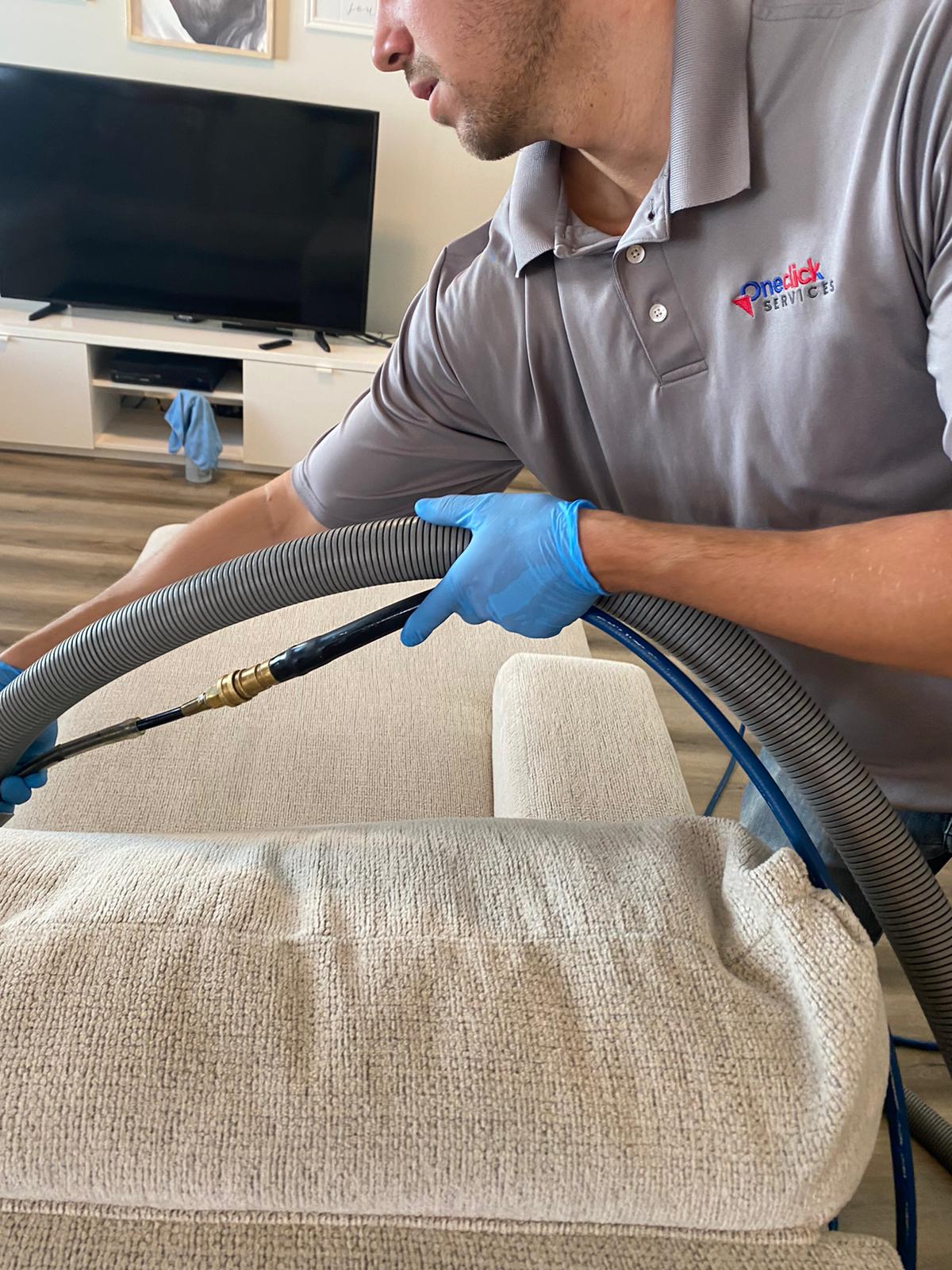 A man is cleaning a rug with a vacuum cleaner in a living room.
