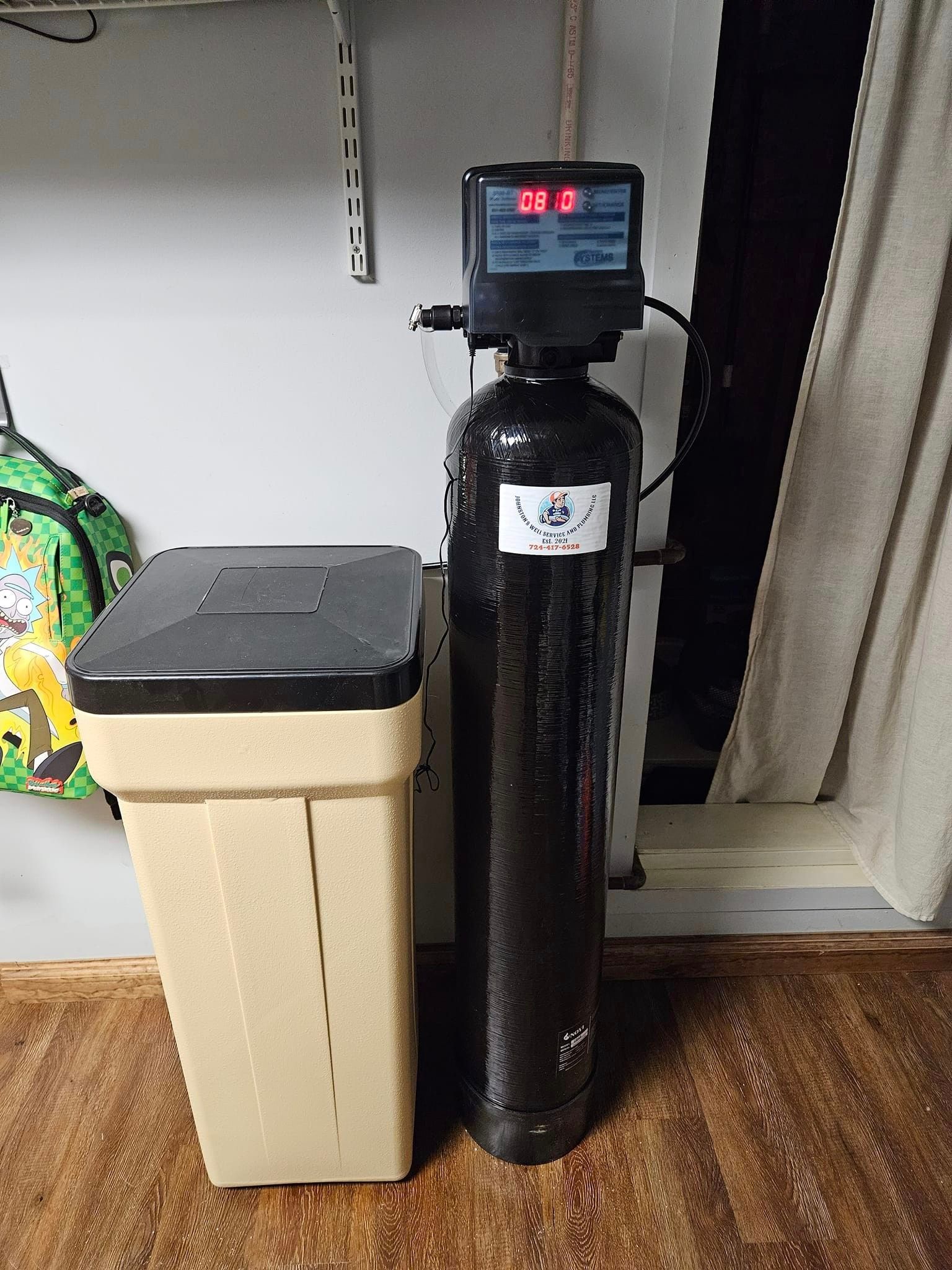 A water softener is sitting next to a trash can in a room.