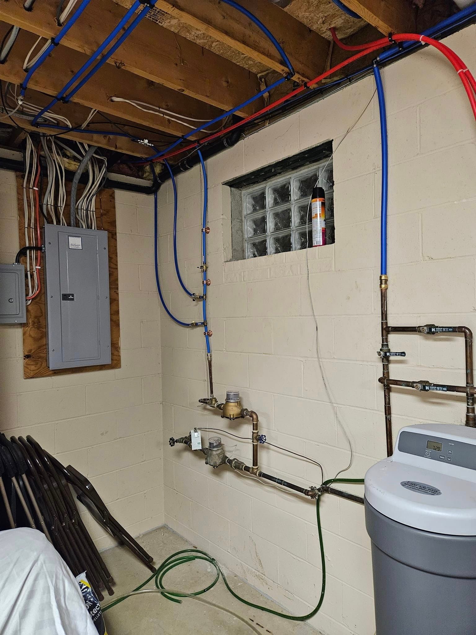 A basement with a washer and dryer and lots of wires hanging from the ceiling.