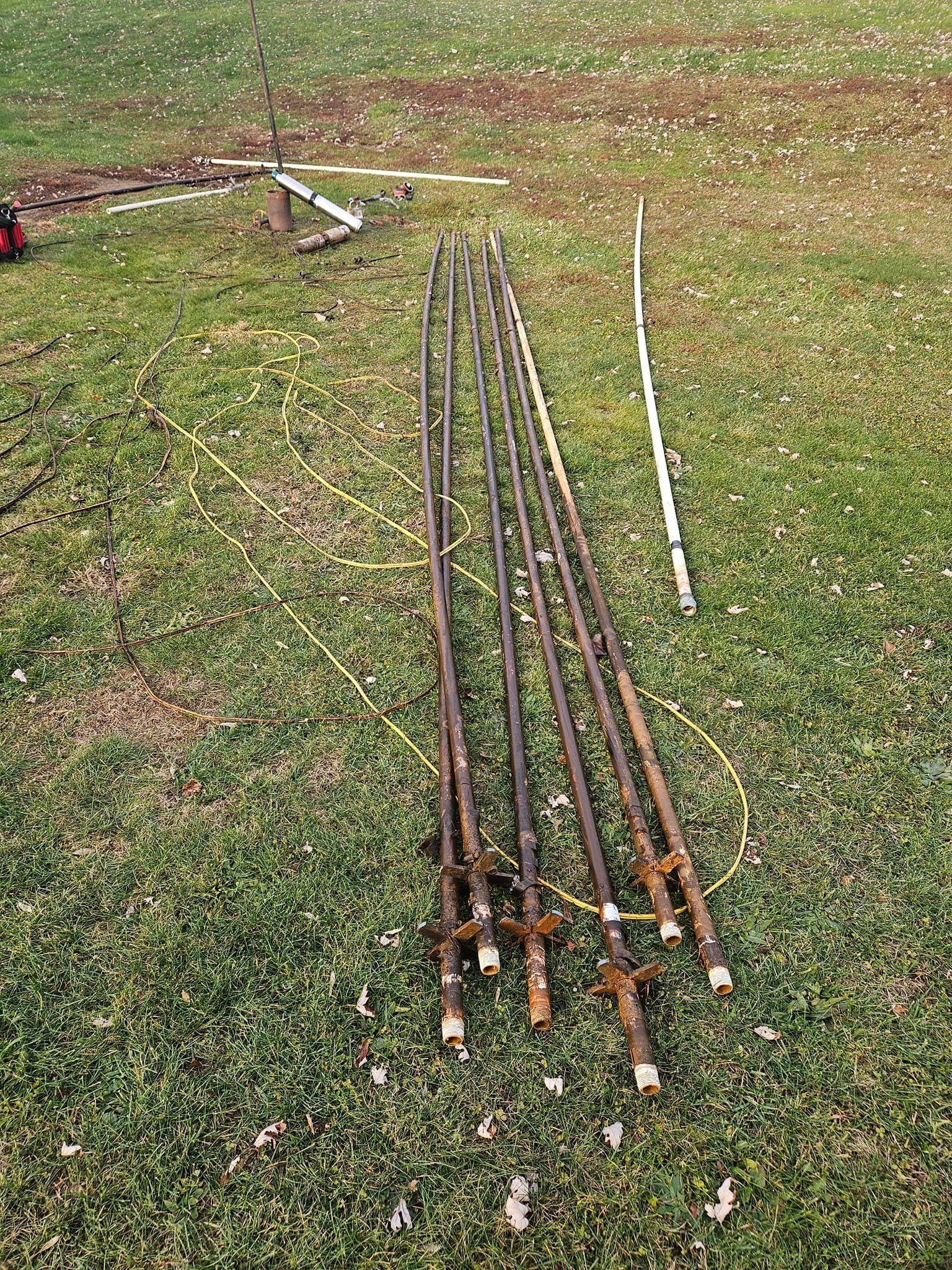 A bunch of fishing rods are sitting on top of a lush green field.