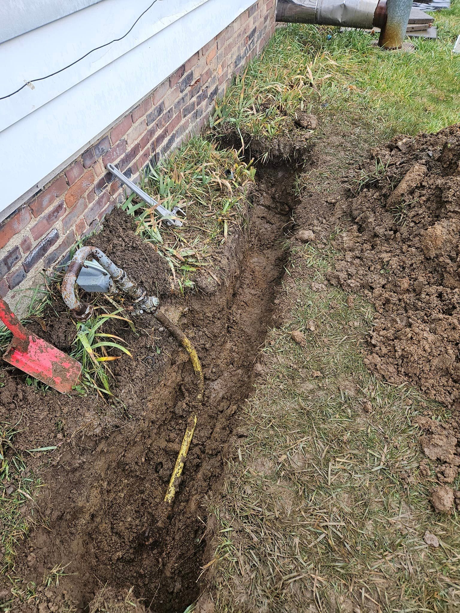 A person is digging a hole in the ground next to a house.