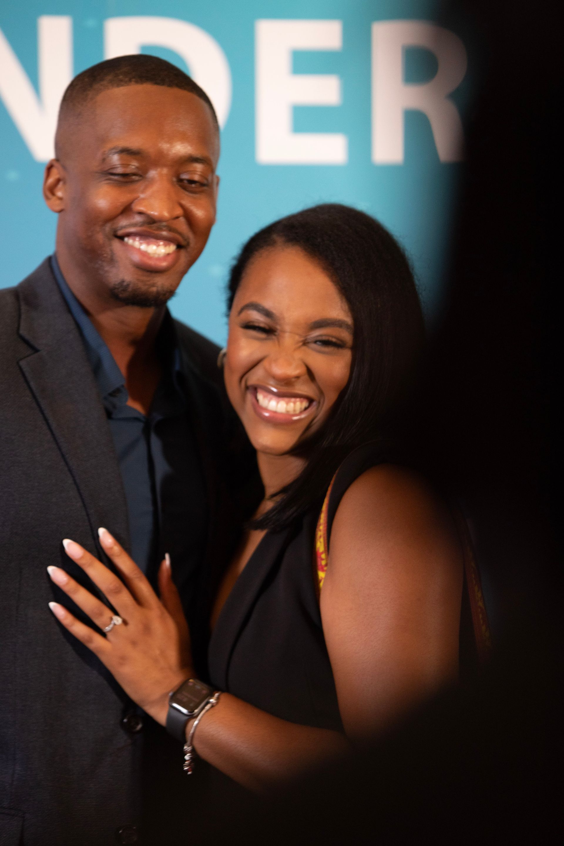 A man and woman are posing for a picture in front of a sign that says nder