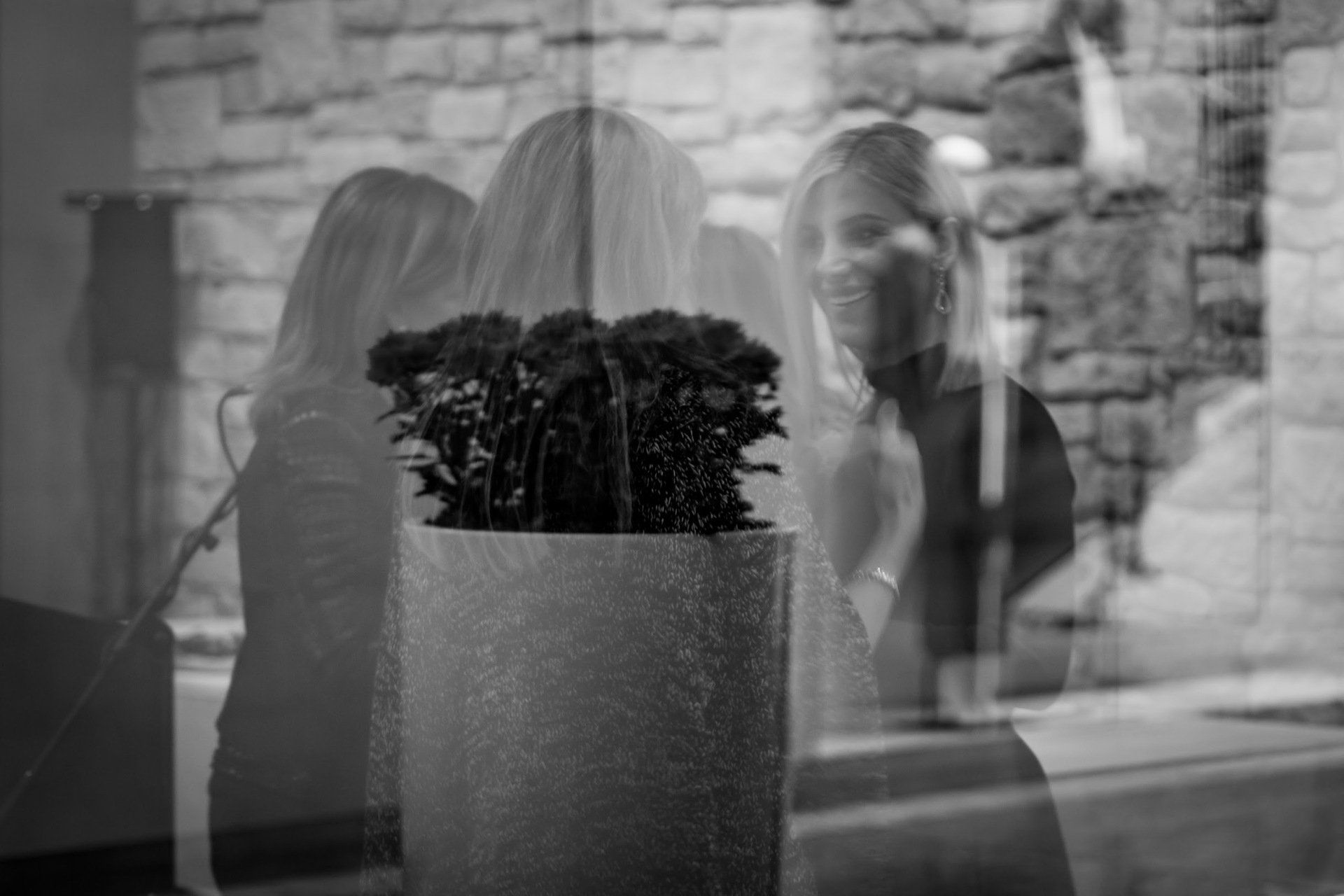 A black and white photo of a woman standing in front of a window.