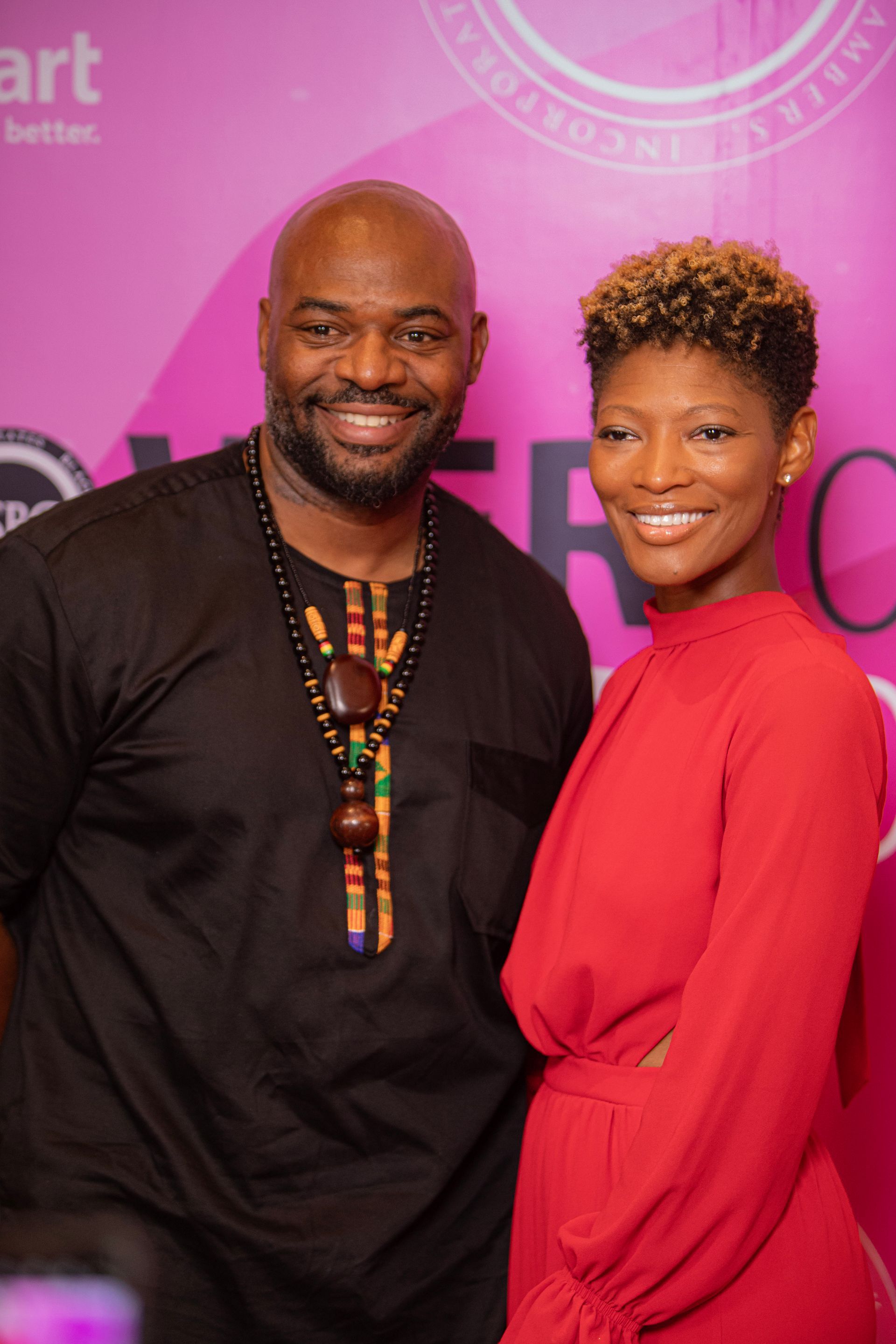 A man and a woman are posing for a picture . the woman is wearing a red dress.