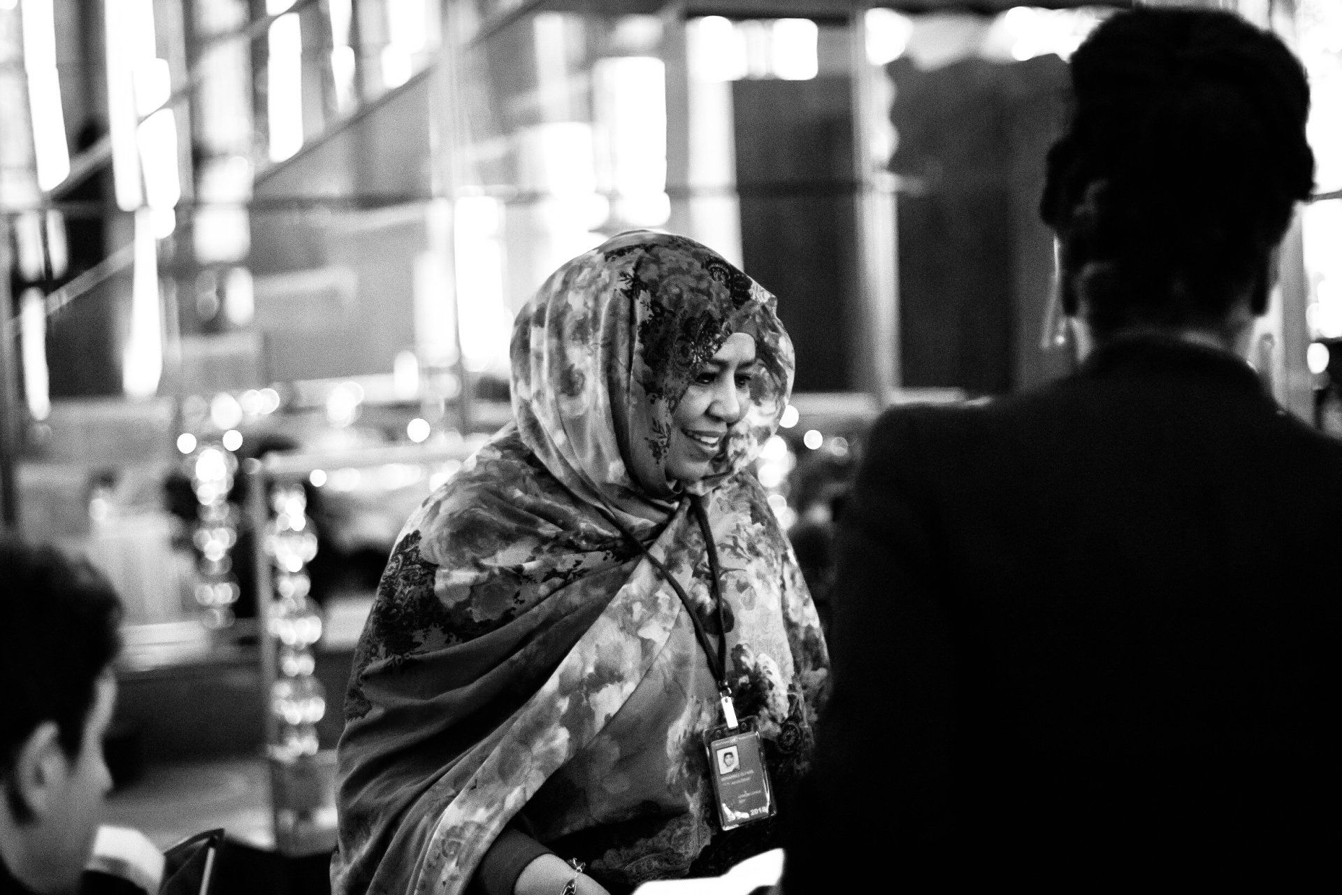 A black and white photo of a woman in a hijab talking to a man.