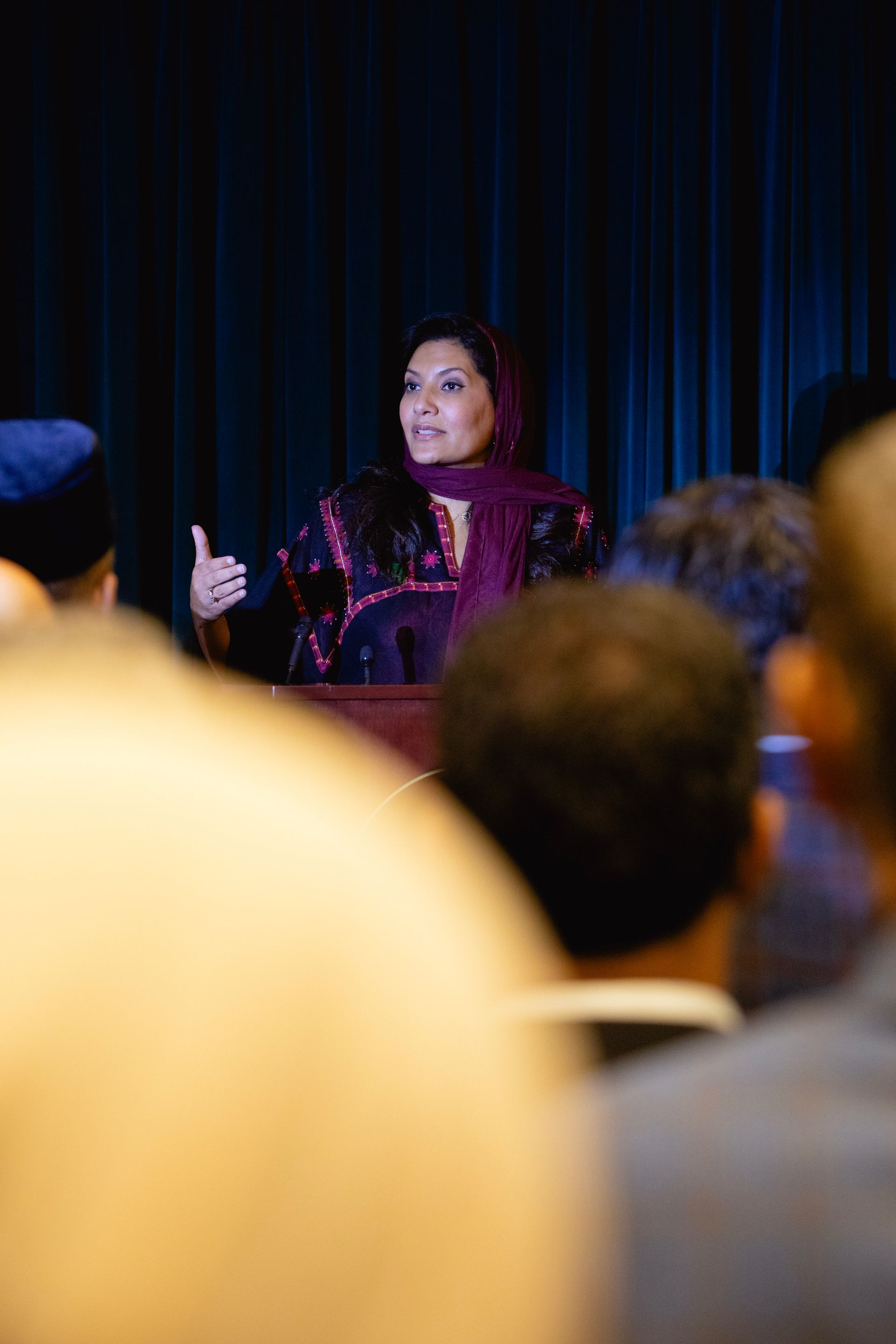A woman is standing at a podium giving a speech to a crowd of people.