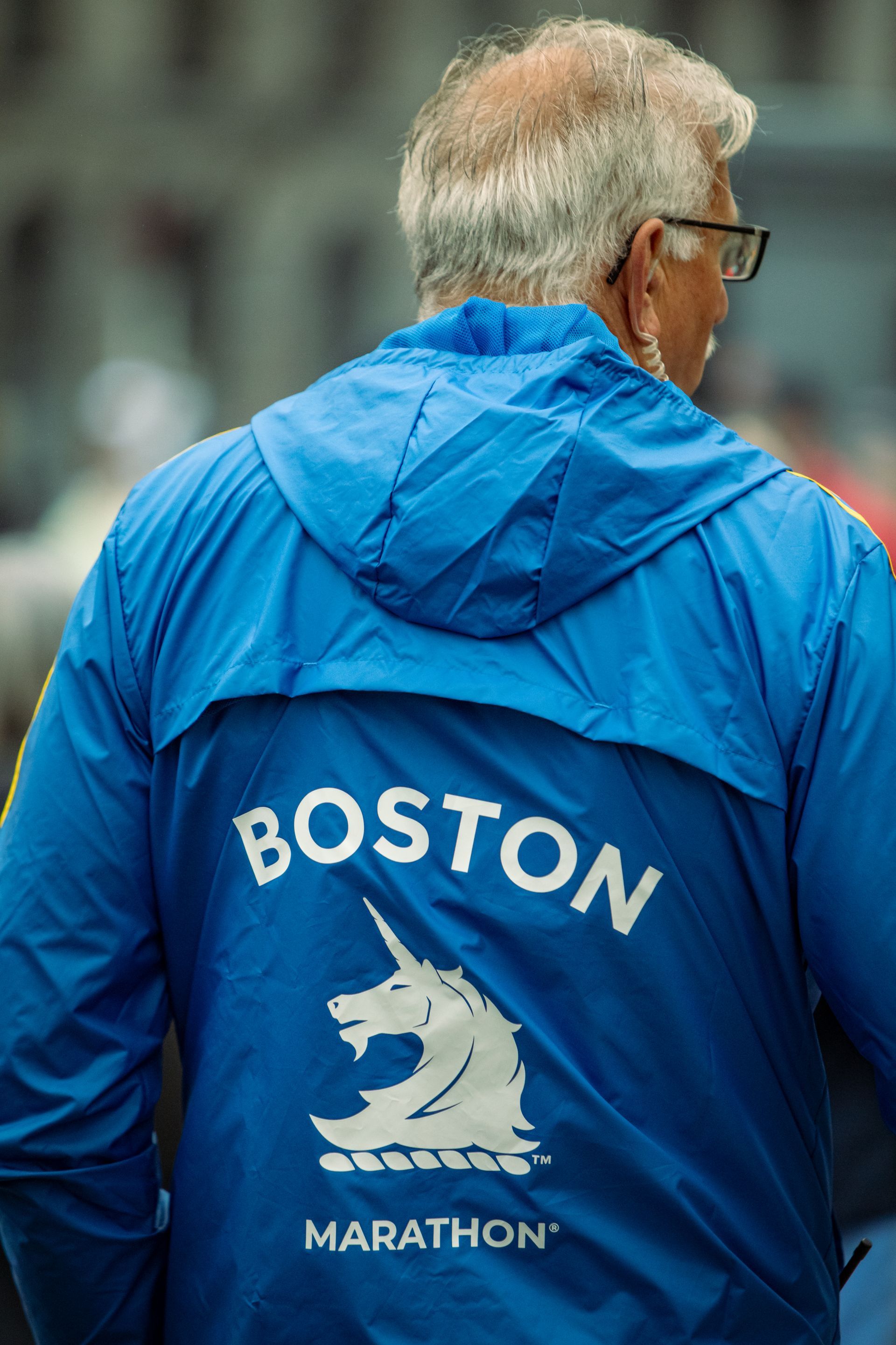 A man is wearing a blue boston marathon jacket