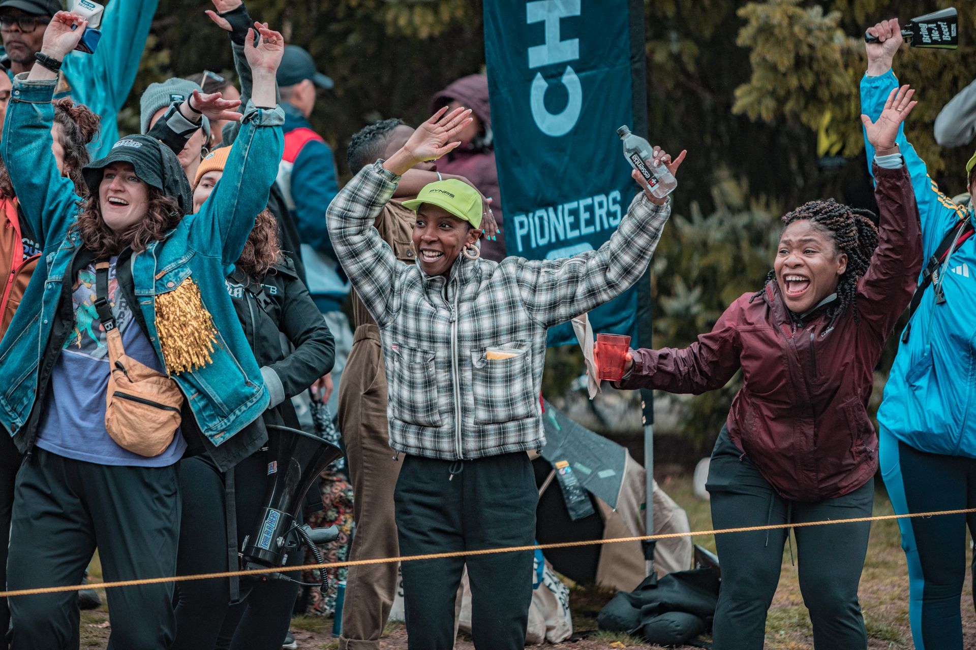A group of people are standing in a field with their arms in the air.