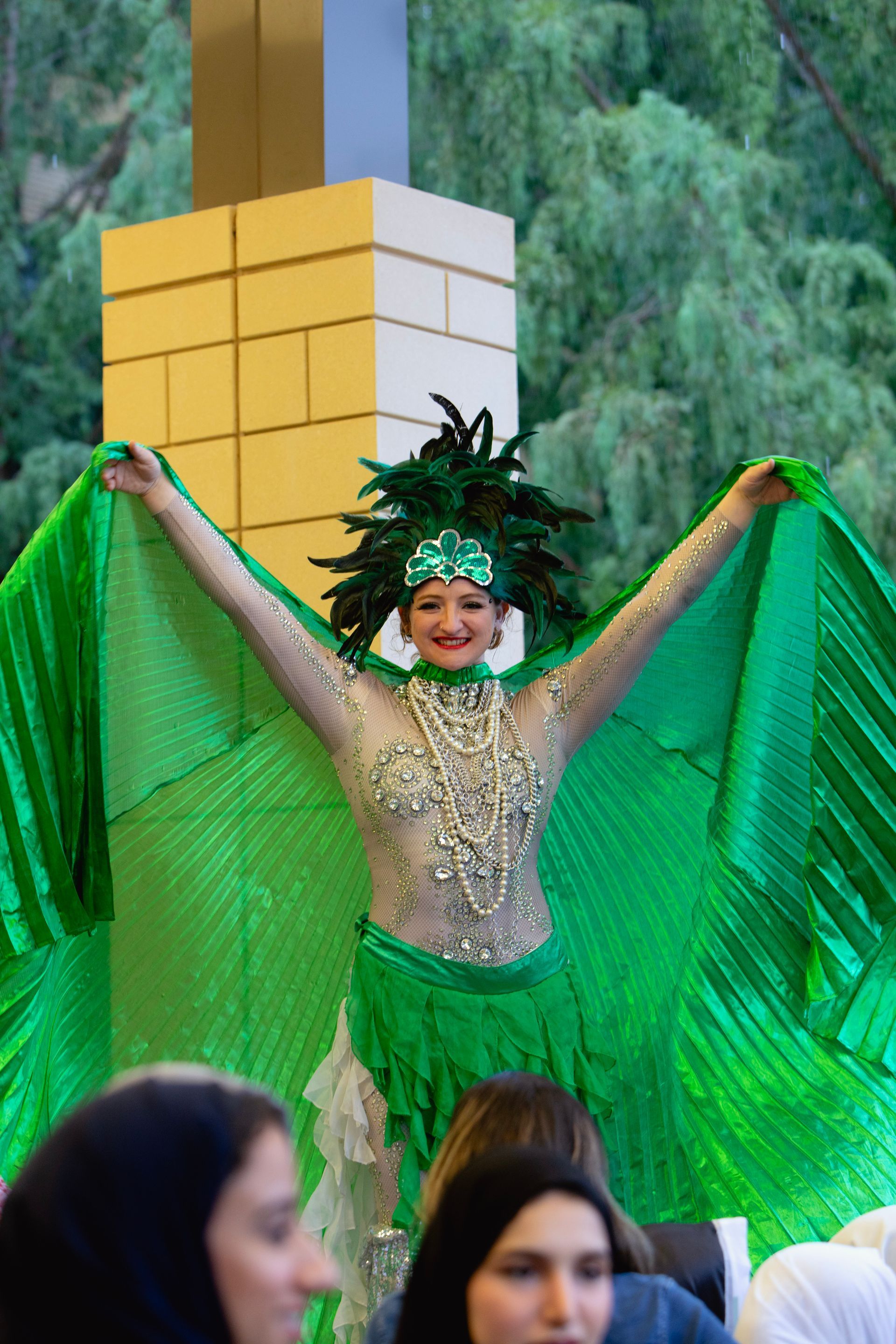 A woman in a green costume is standing in front of a group of people.