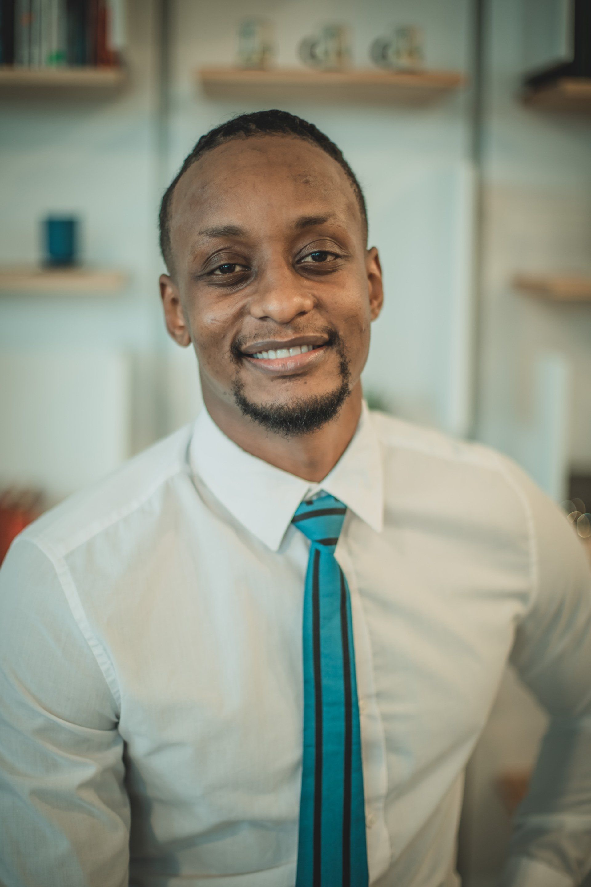 A man in a white shirt and blue tie is smiling for the camera.