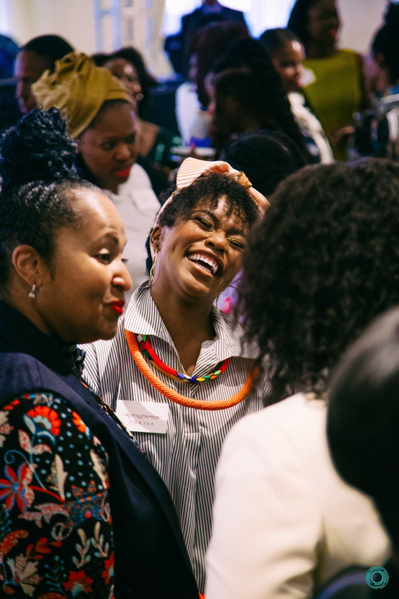 A group of women are laughing and talking to each other in a room.