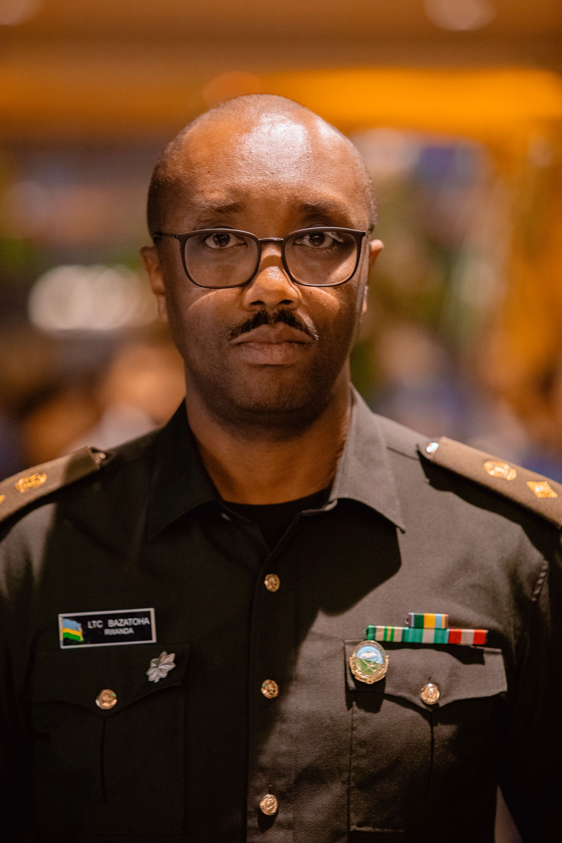 A man in a military uniform and glasses is standing in front of a crowd.