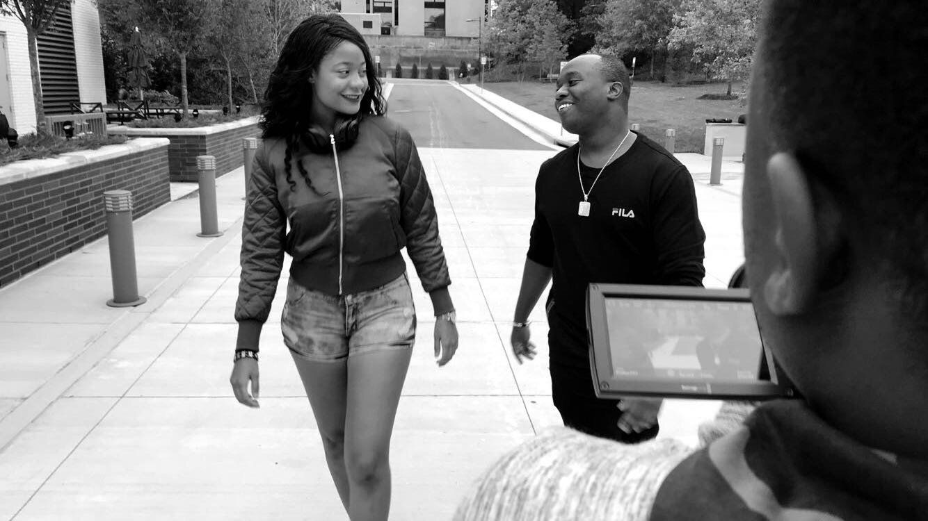 A black and white photo of a man and a woman walking down a sidewalk.