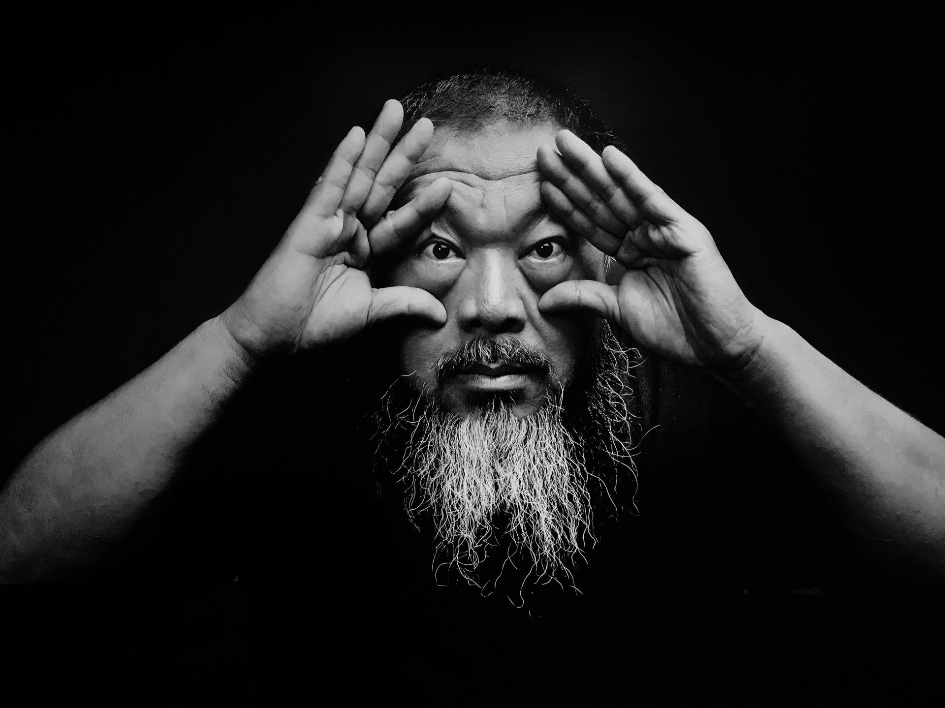 A man with a beard is making a funny face with his hands.