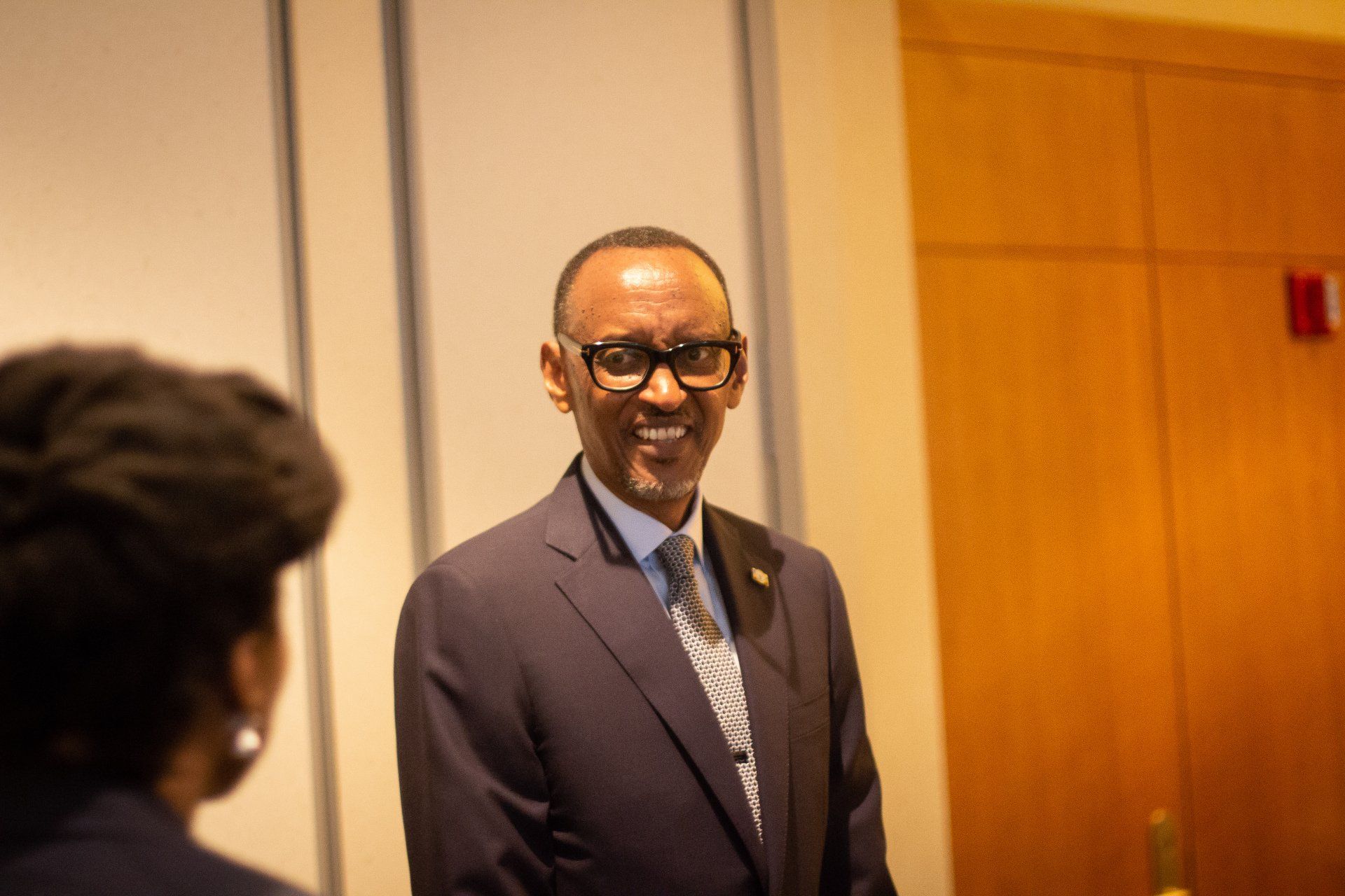 A man in a suit and tie is talking to a woman in a room.