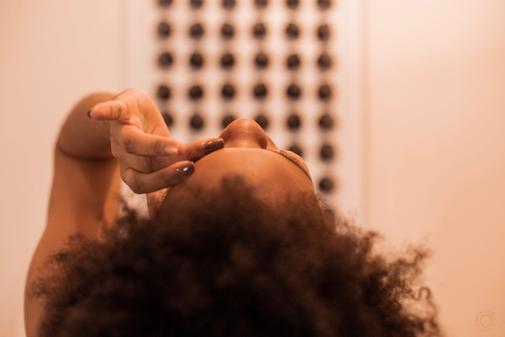 A woman with curly hair is looking at herself in the mirror.