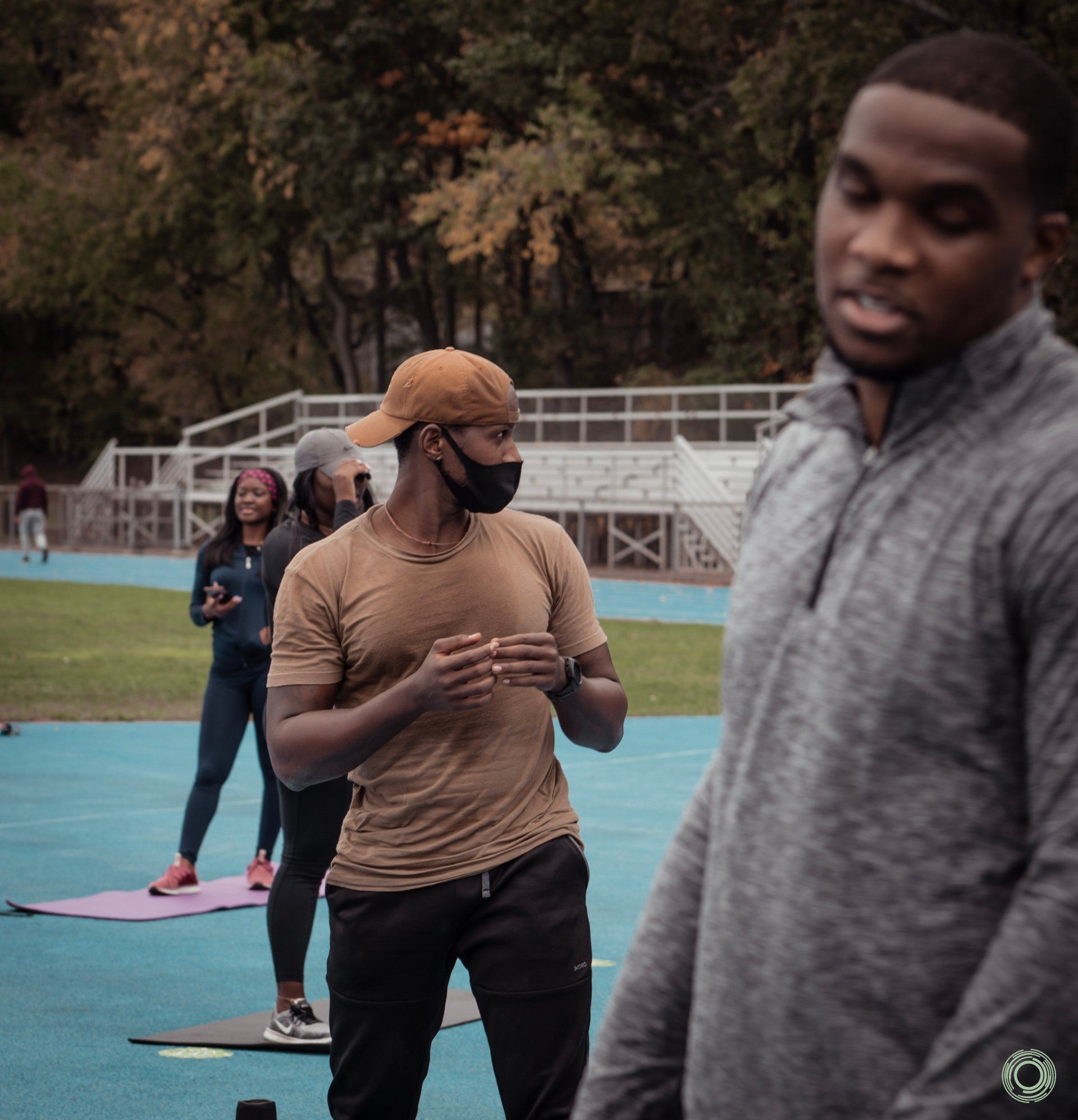 A man wearing a mask stands next to another man on a track