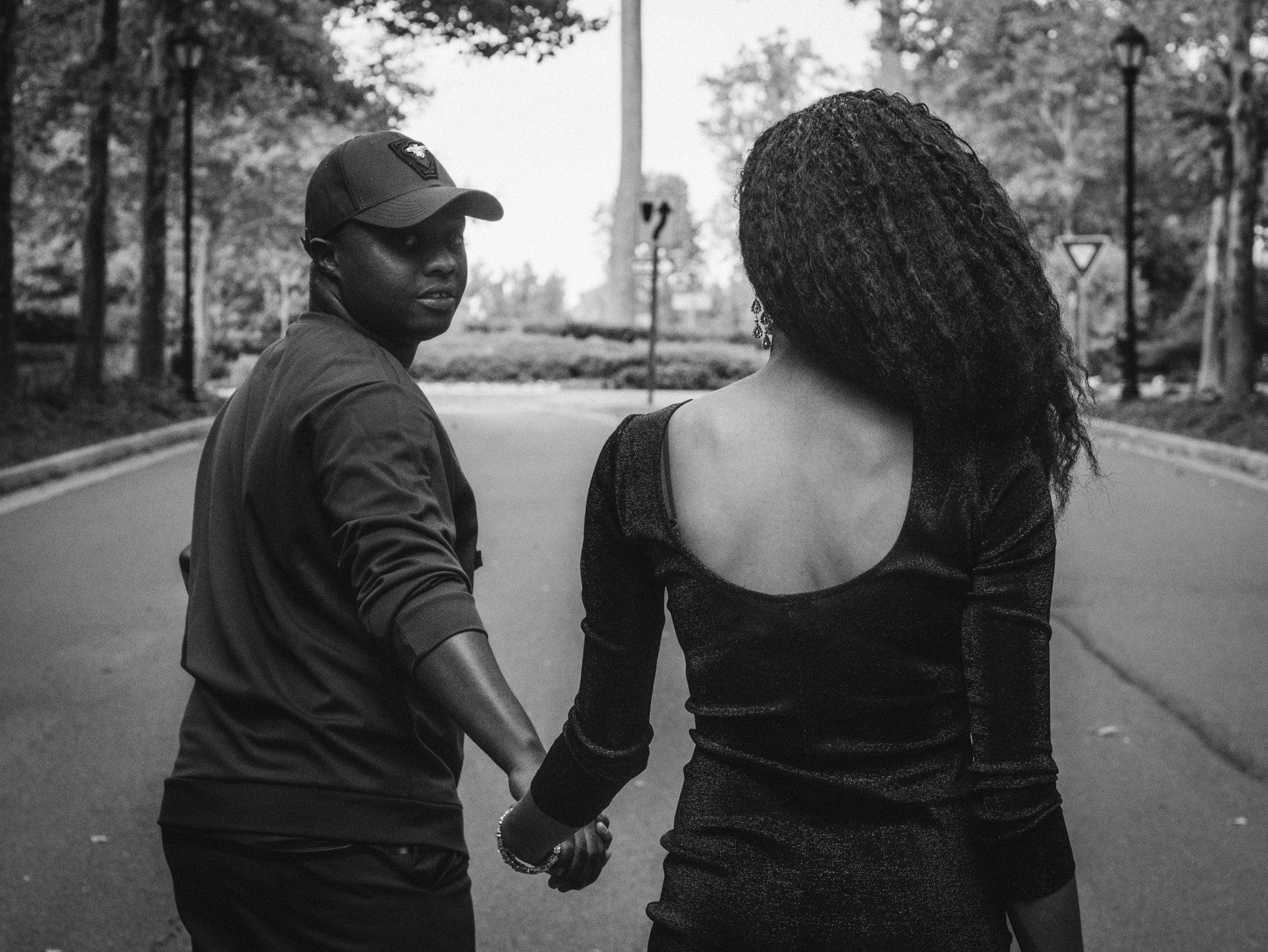 A man and a woman are holding hands while walking down a street.