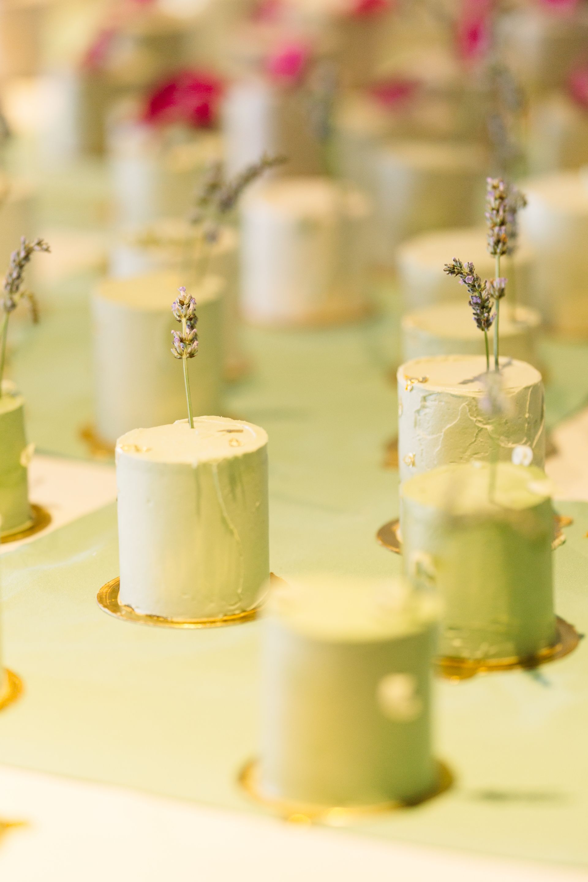 A row of small white cakes with lavender on top are sitting on a table.