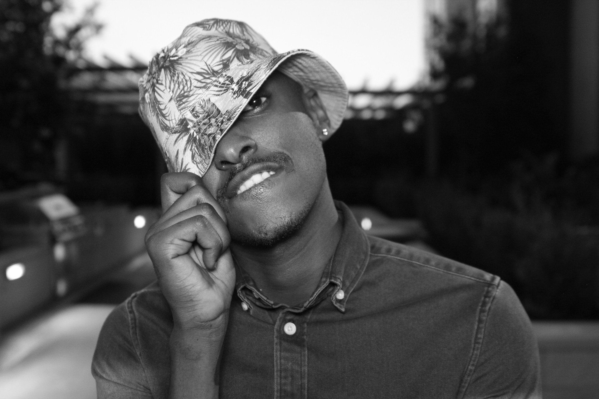 A black and white photo of a man wearing a hat covering his face.