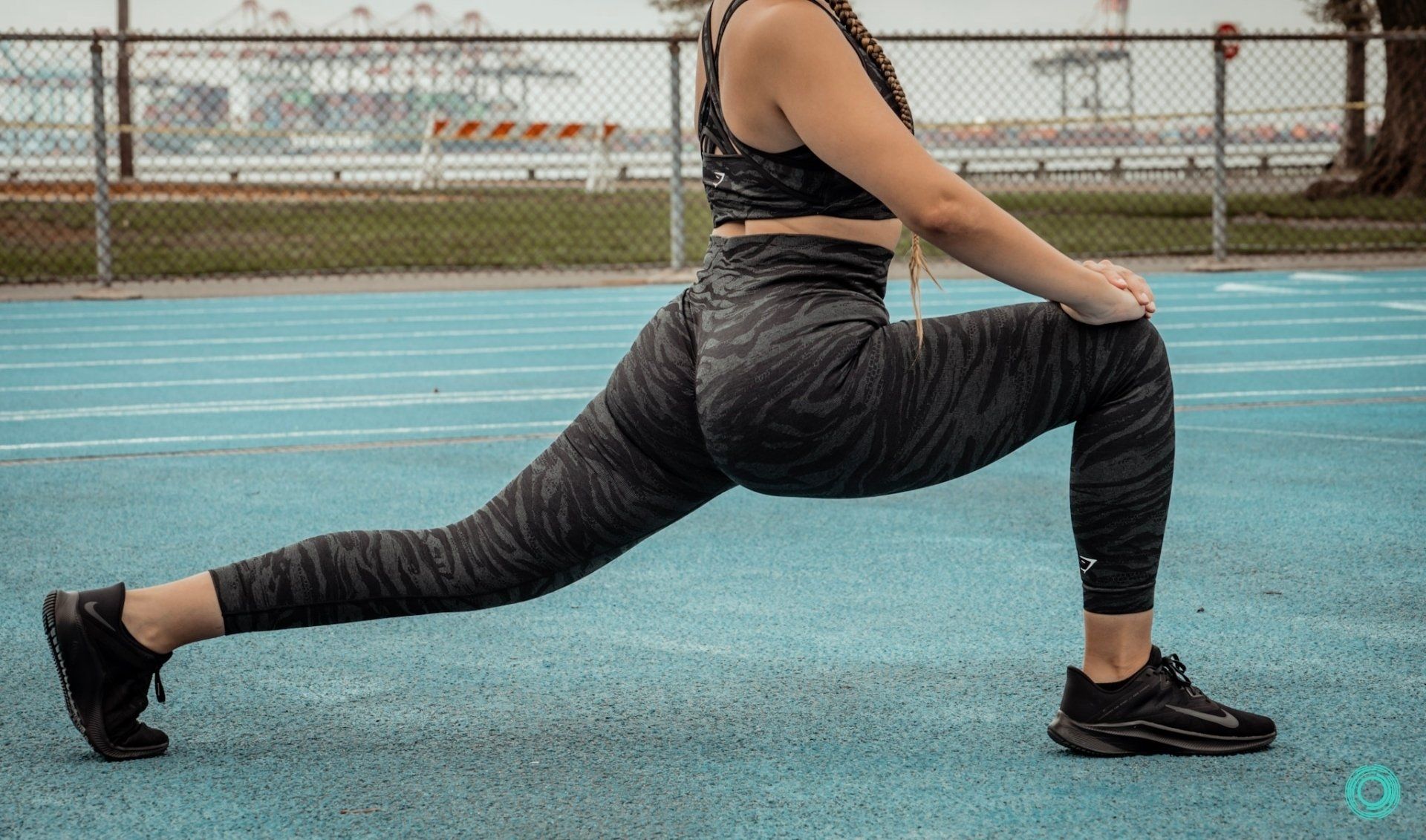 A woman is stretching her legs on a track.