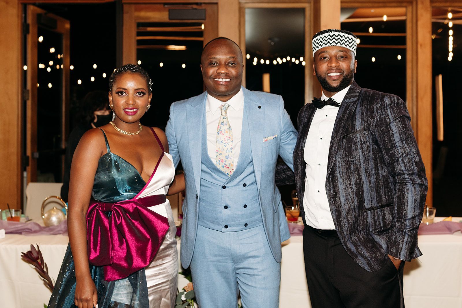 A man in a suit and tie is standing next to a woman in a dress and a man in a tuxedo.