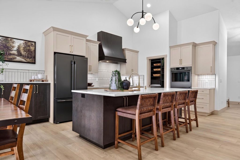 Bright modern kitchen with island, wood bar stools, black appliances, and white cabinetry