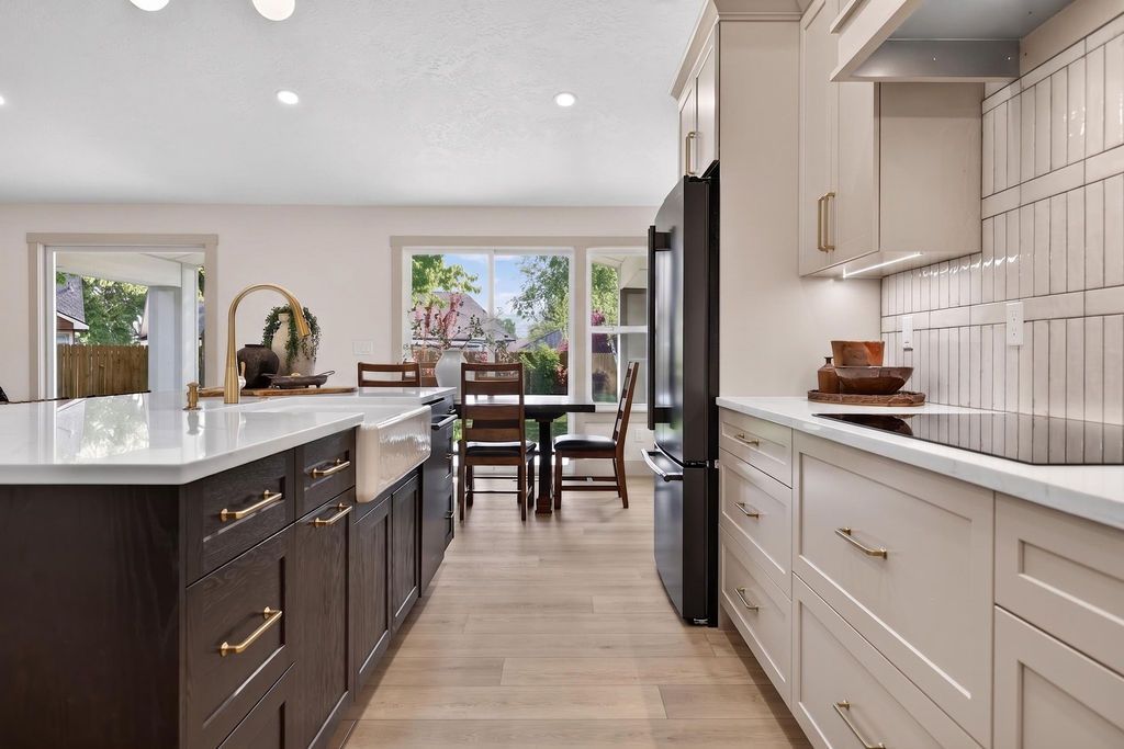 Modern kitchen with long island, white cabinetry, dark lower cabinets, and dining area beyond.