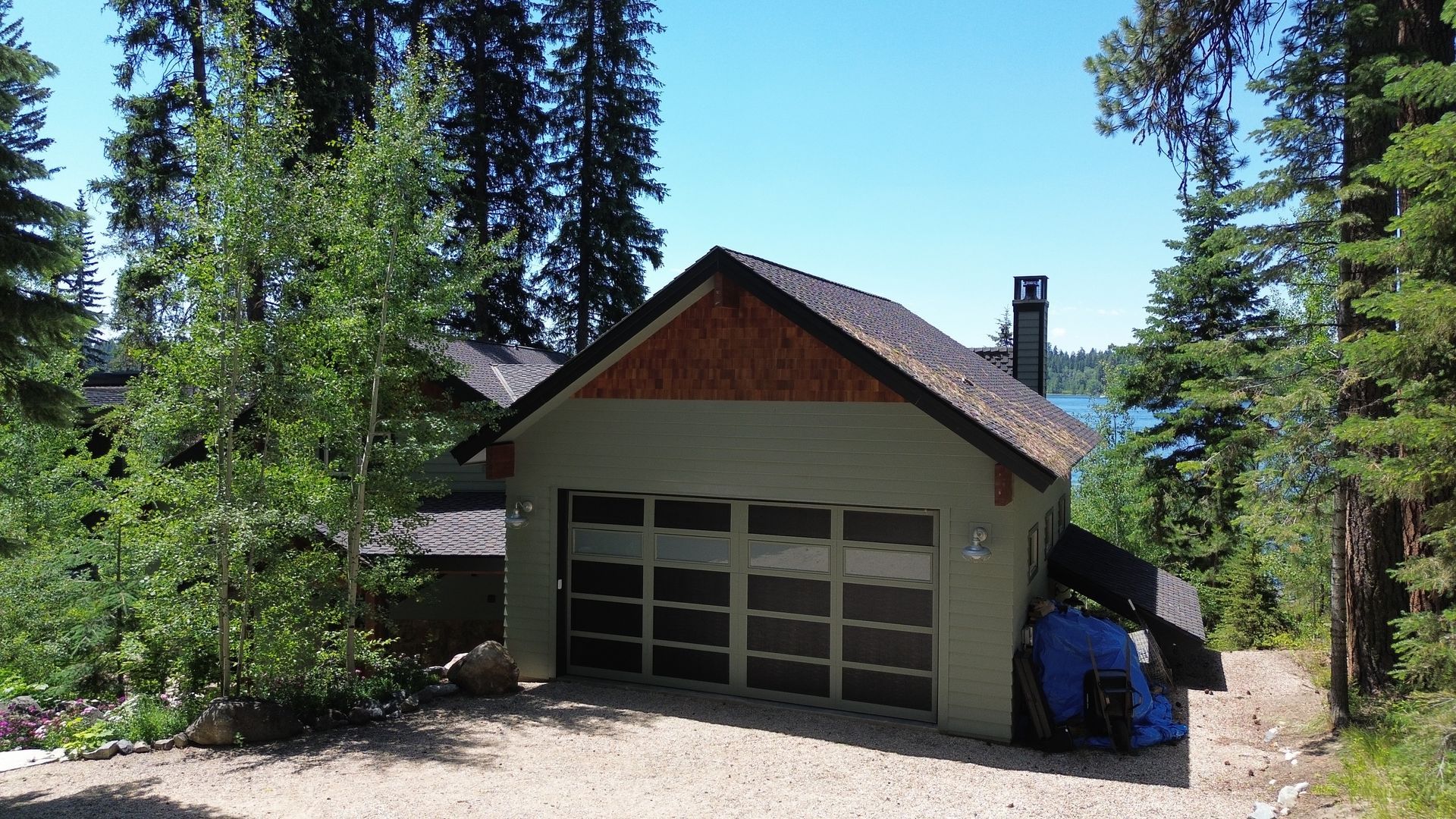 Cabin-like garage with a white door among tall pine trees on a sunny day