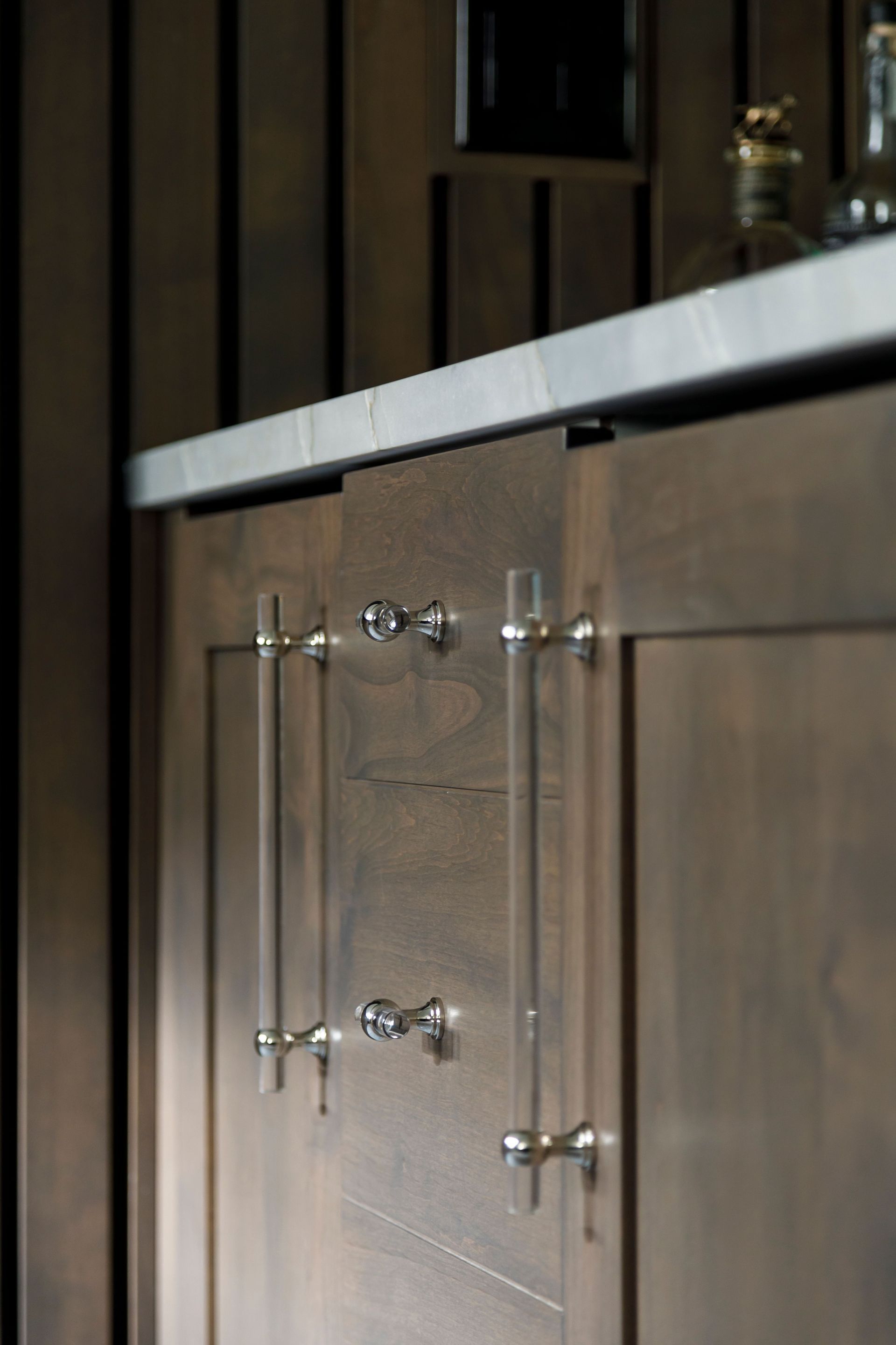 Glass-front cabinet beneath a marble countertop in a kitchen.